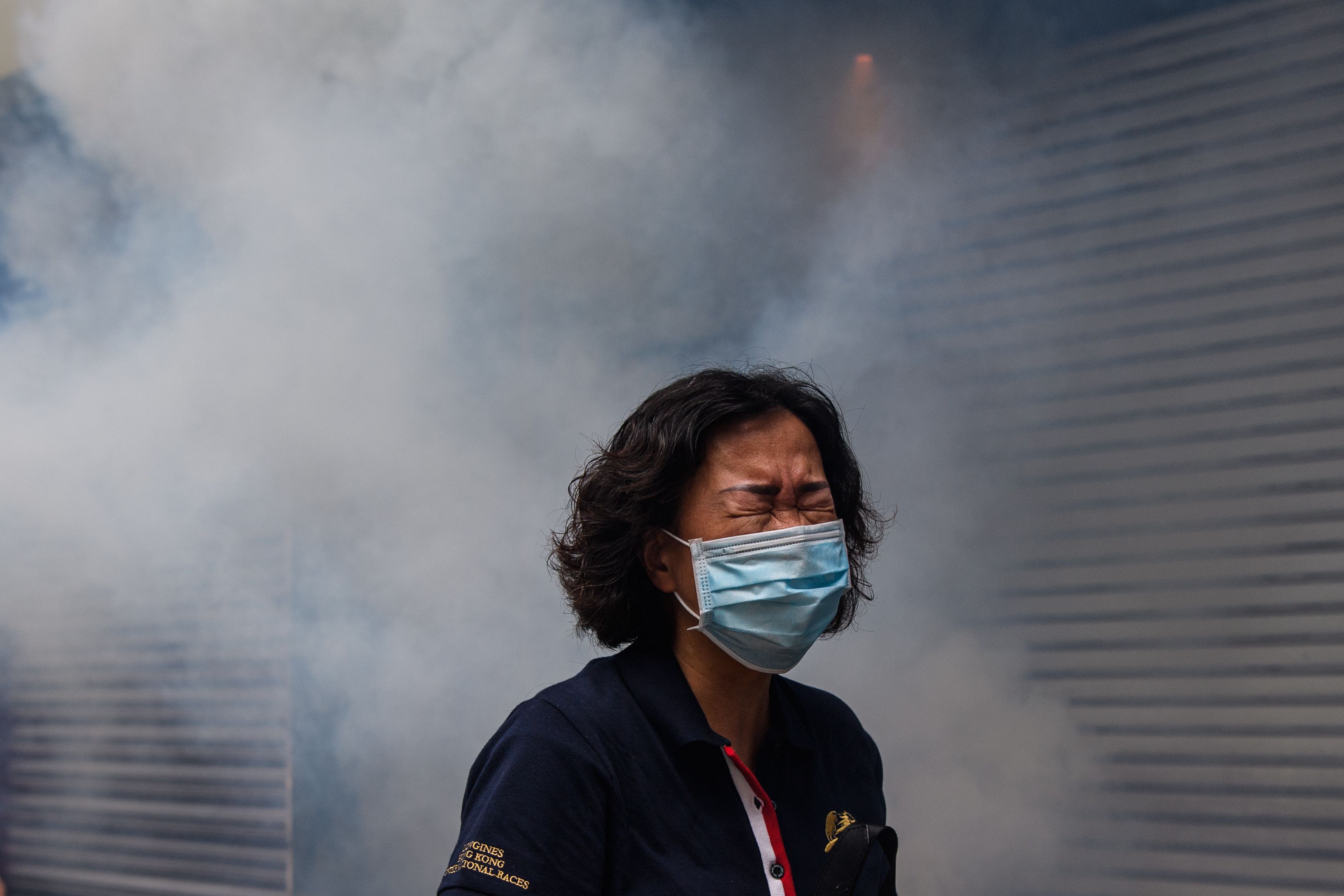 TOPSHOT - A woman reacts after riot police fired tear gas to disperse protesters taking part in a pro-democracy rally against a proposed new security law in Hong Kong on May 24, 2020. - Police fired tear gas and water cannon at thousands of Hong Kong pro-democracy protesters who gathered on May 24 against a controversial security law proposed by China, in the most intense clashes in months. (Photo by ANTHONY WALLACE / AFP)