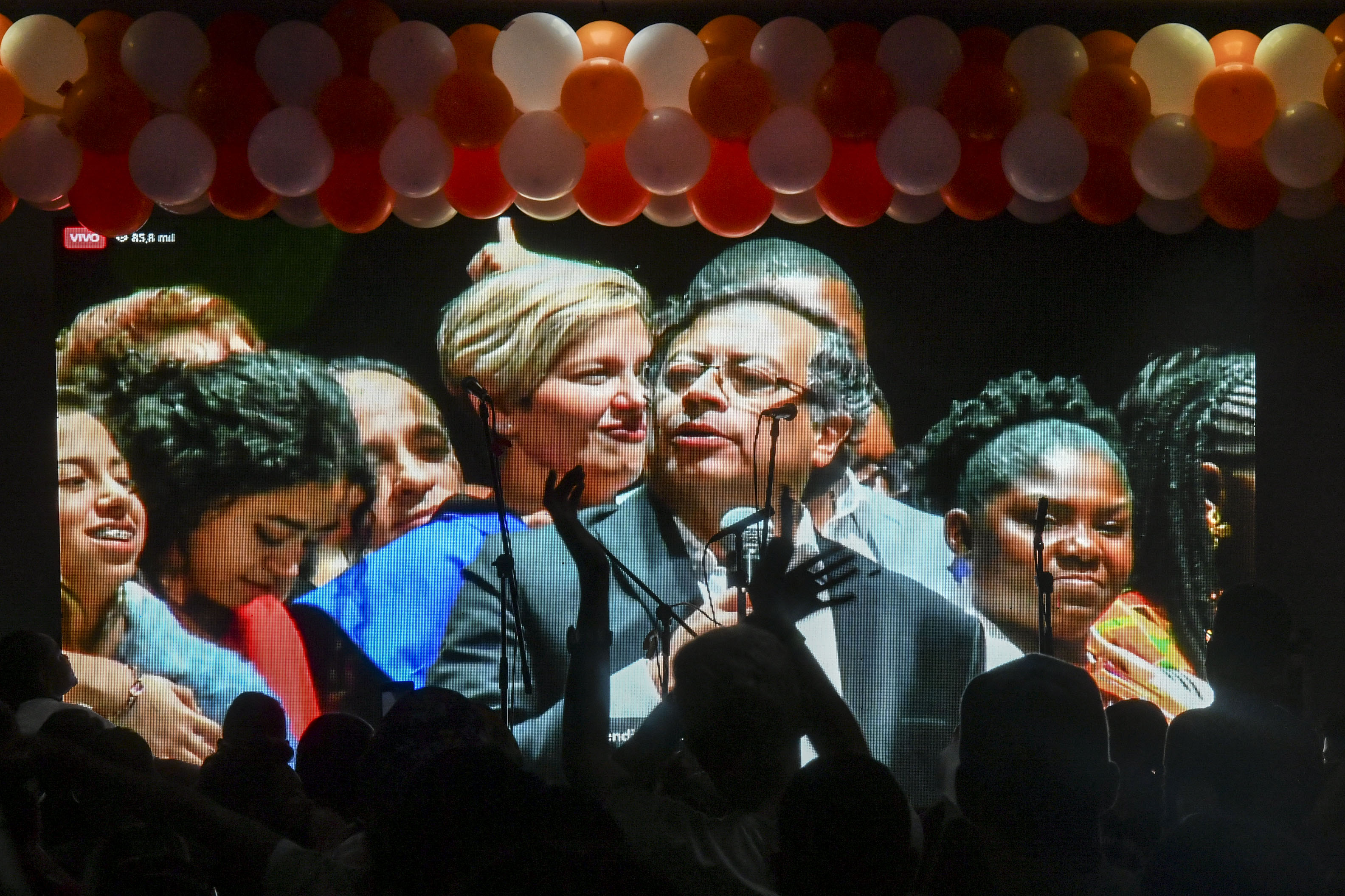 Supporters of Colombian left-wing presidential candidate Gustavo Petro watch him speaking on a screen in Medellin, Colombia, on June 19, 2022 after the presidential runoff election. - Ex-guerrilla Gustavo Petro was elected the first ever left-wing president of crisis-wracked Colombia on Sunday after beating millionaire businessman Rodolfo Hernandez in a tense and unpredictable runoff election. (Photo by JOAQUIN SARMIENTO / AFP)