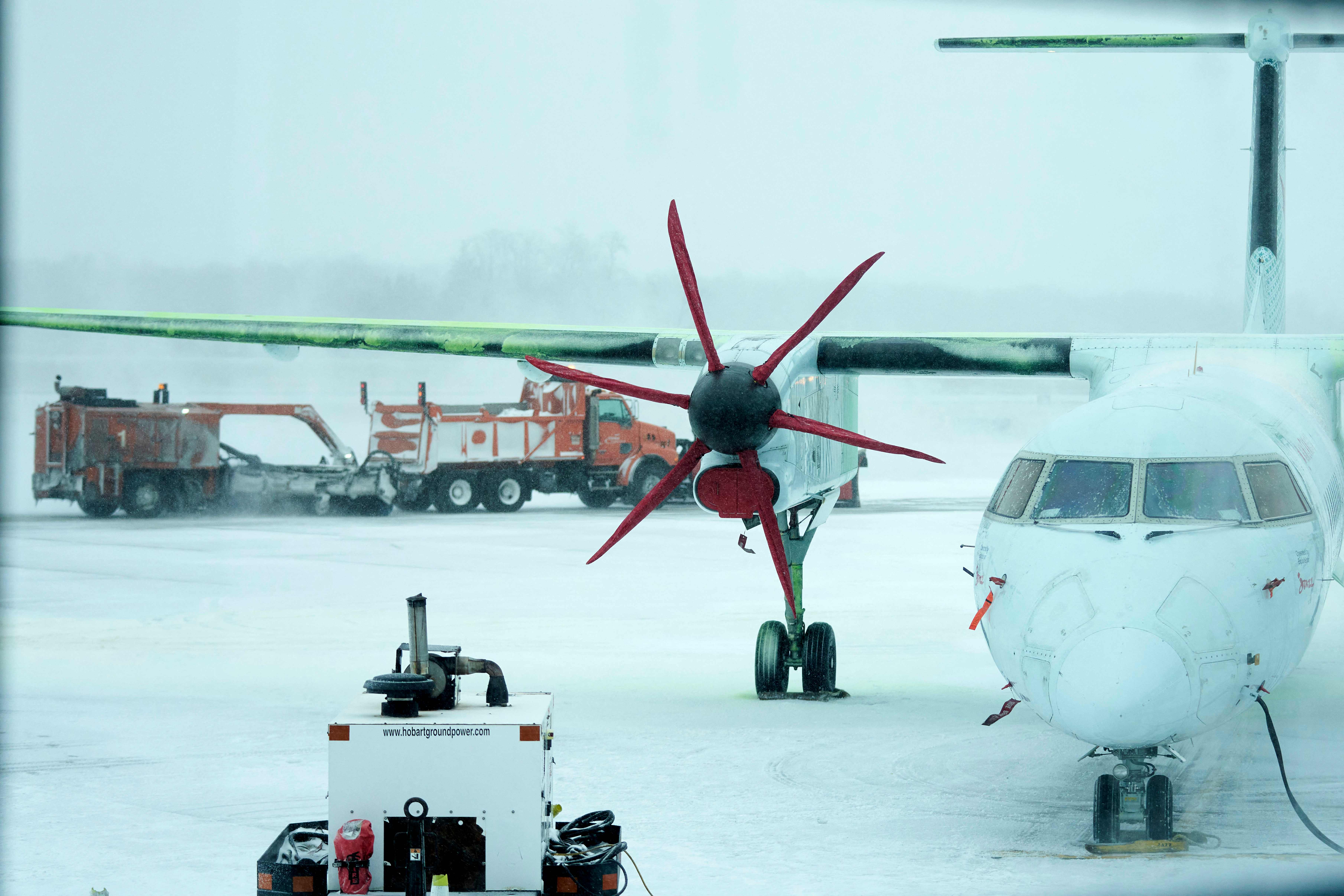 An Air Canada plane sits on the apron at the London International Airport as crews work to keep runways clear during a large winter storm in London, Ontario, Canada, December 23, 2022. - Schools and some highways in the region were closed, and air travel was disrupted as the system made its way across the province. (Photo by Geoff Robins / AFP)