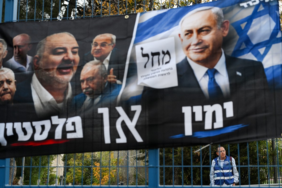Un voluntario permanece detrás de una pancarta del partido Likud, del primer ministro israelí, Benjamin Netanyahu, en un centro de votación en Jerusalén, el 27 de octubre de 2026, durante las elecciones legislativas de Israel.