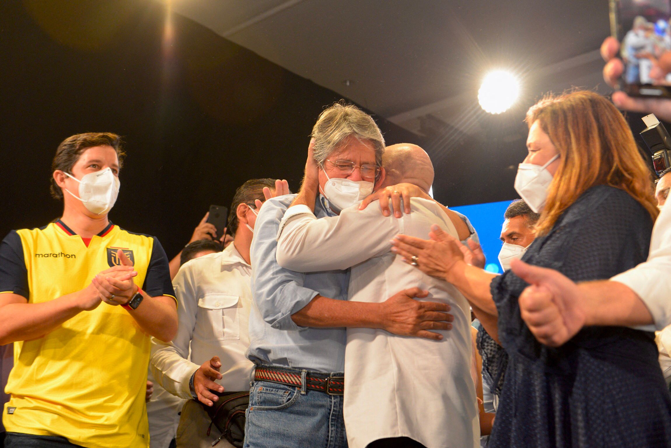 Ecuadorean President-elect Guillermo Lasso (C) and his Vice President Alfredo Borrero (R) hug as they celebrate their victory after knowing the preliminary results of the election runoff at the Conventions Center in Guayaquil, Ecuador on April 11, 2021. - Guillermo Lasso had a lead of five percentage points over Andres Arauz in Ecuador's general election on Sunday after 97 percent of the votes were counted, according to the National Electoral Council. (Photo by Fernando Mendez / AFP)