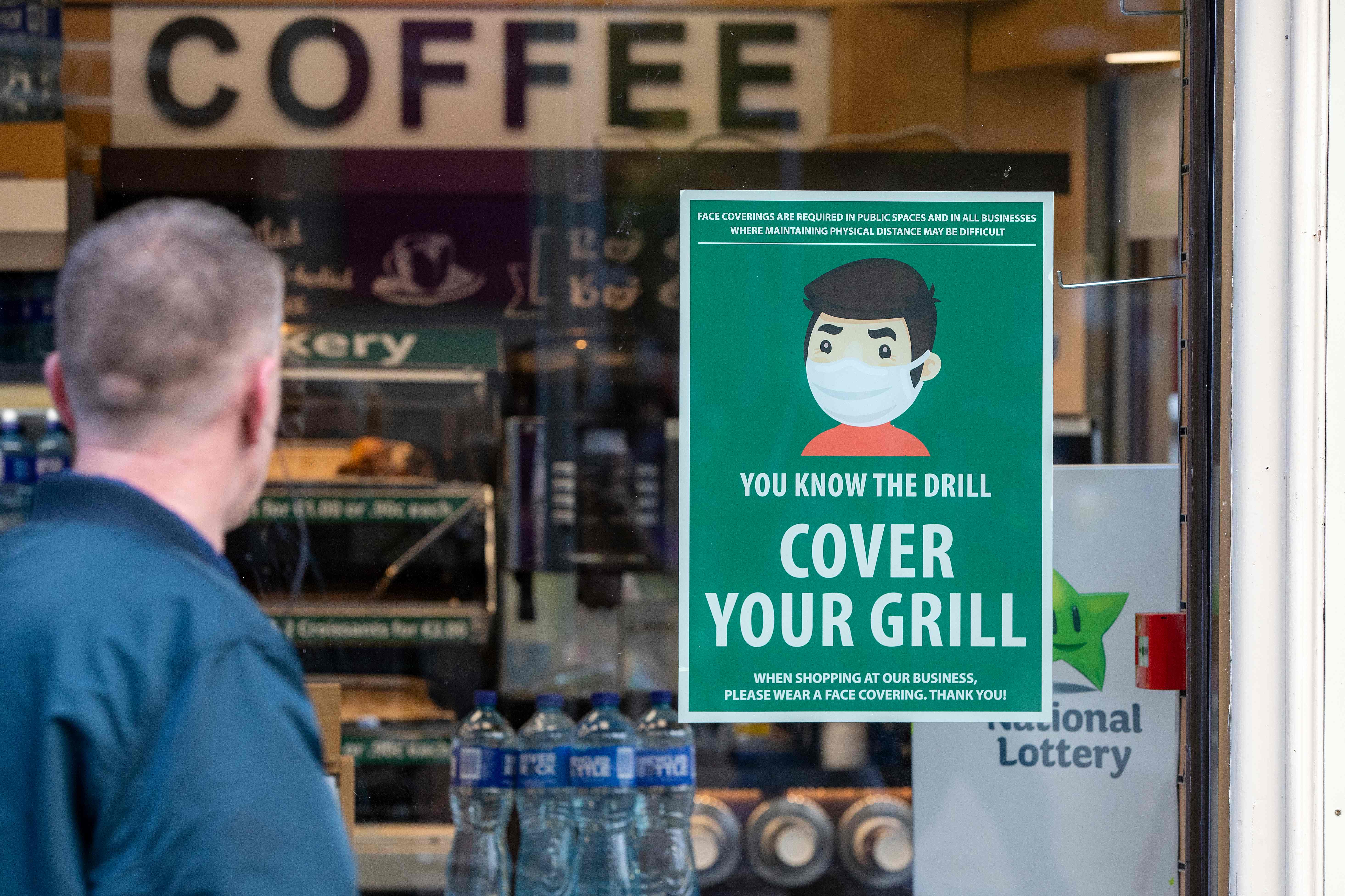 An information poster advising the wearing of face coverings as a precaution against the spread of the novel coronavirus covid-19 is seen on the window of a coffee shop in Dublin on October 21, 2020 as Ireland prepares to enter a second national lockdown to stem the spread of the virus that causes Covid-19. - Millions of people in Ireland were getting set for a second national lockdown on October 21, the first European country to take the drastic step as the continent battles a persistent surge in coronavirus cases. (Photo by Paul Faith / AFP)