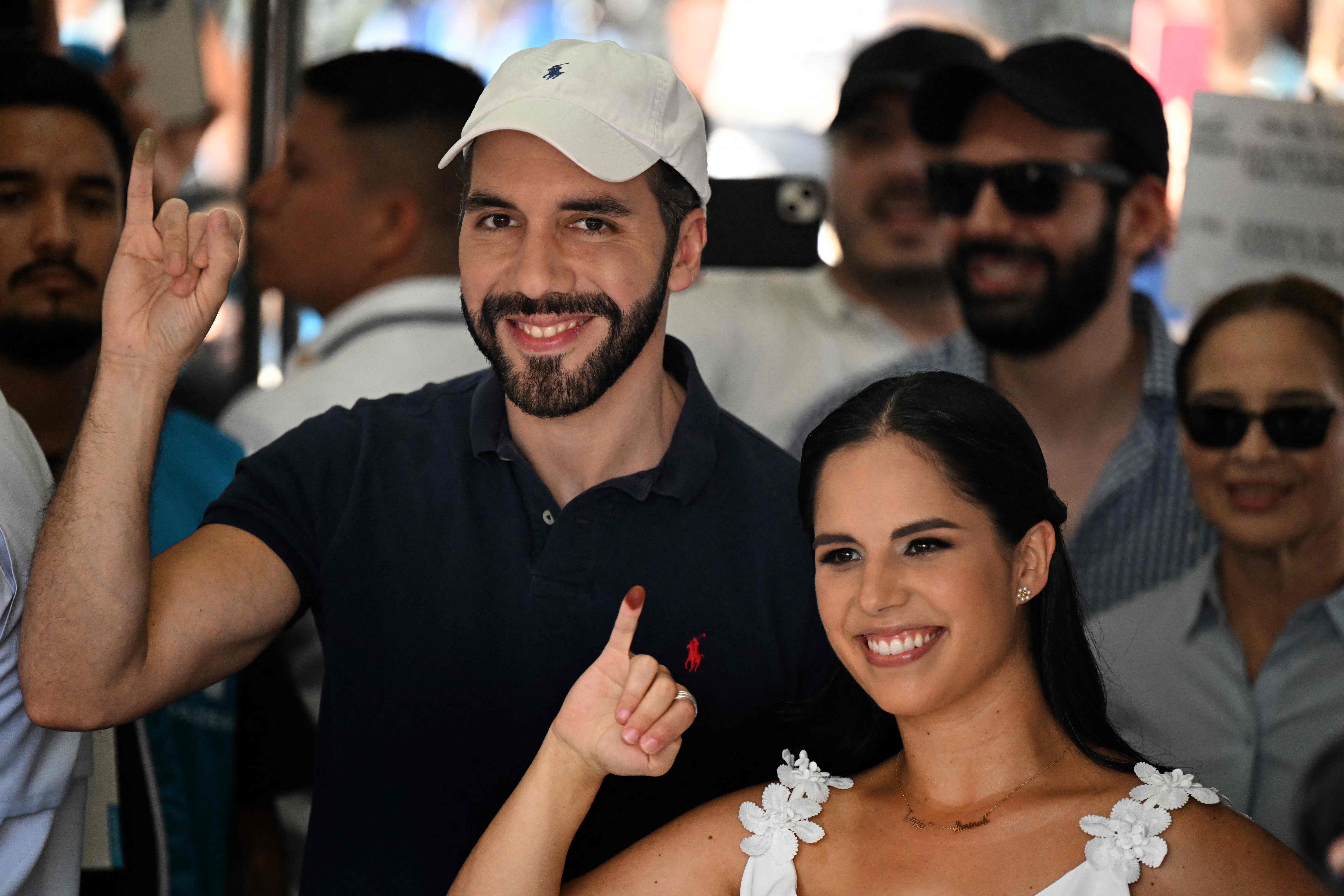 El presidente de El Salvador, Nayib Bukele, y su esposa Gabriela Rodríguez muestran sus dedos entintados después de votar en un colegio electoral durante las elecciones municipales en San Salvador, el domingo 3 de marzo. (Foto de Marvin RECINOS / AFP)