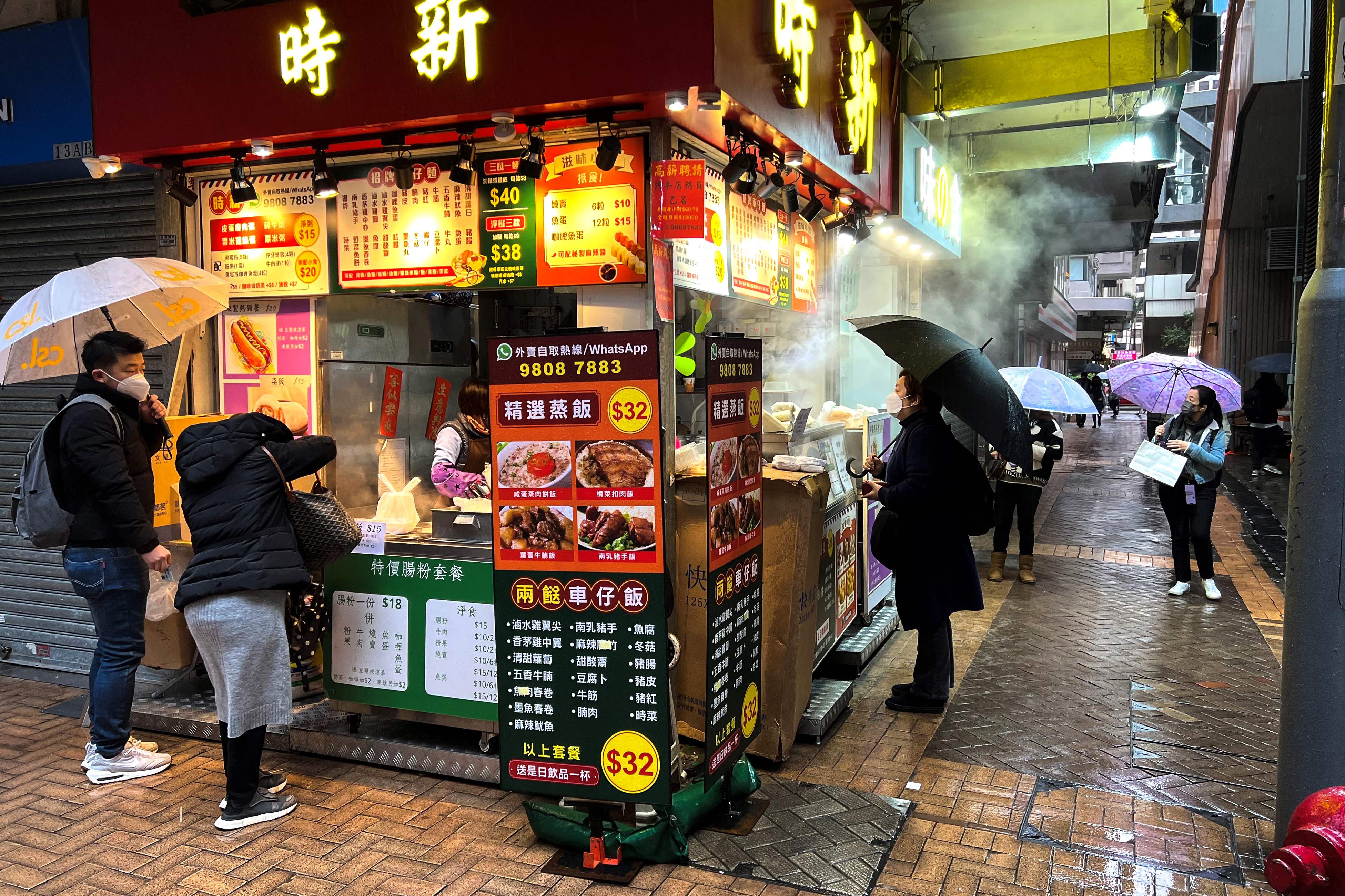 People buy food from a stall in Wan Chai district of Hong Kong as a winter monsoon brought cold and windy weather forcing authorities to issue a cold weather warning. (Photo by Mladen ANTONOV / AFP)