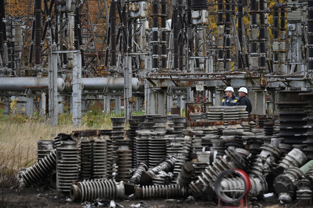 (FILES) In this file photo taken on October 27, 2022, workers examine damage as they repair power line equipment destroyed after a missile strike on a power plant, in an undisclosed location of Ukraine, amid the Russian invasion of Ukraine. - Russian drones and missile strikes led to power cuts in "hundreds of settlements" across seven Ukrainian regions on Monday, Prime Minister Denys Shmyhal said. (Photo by Sergei SUPINSKY / AFP)