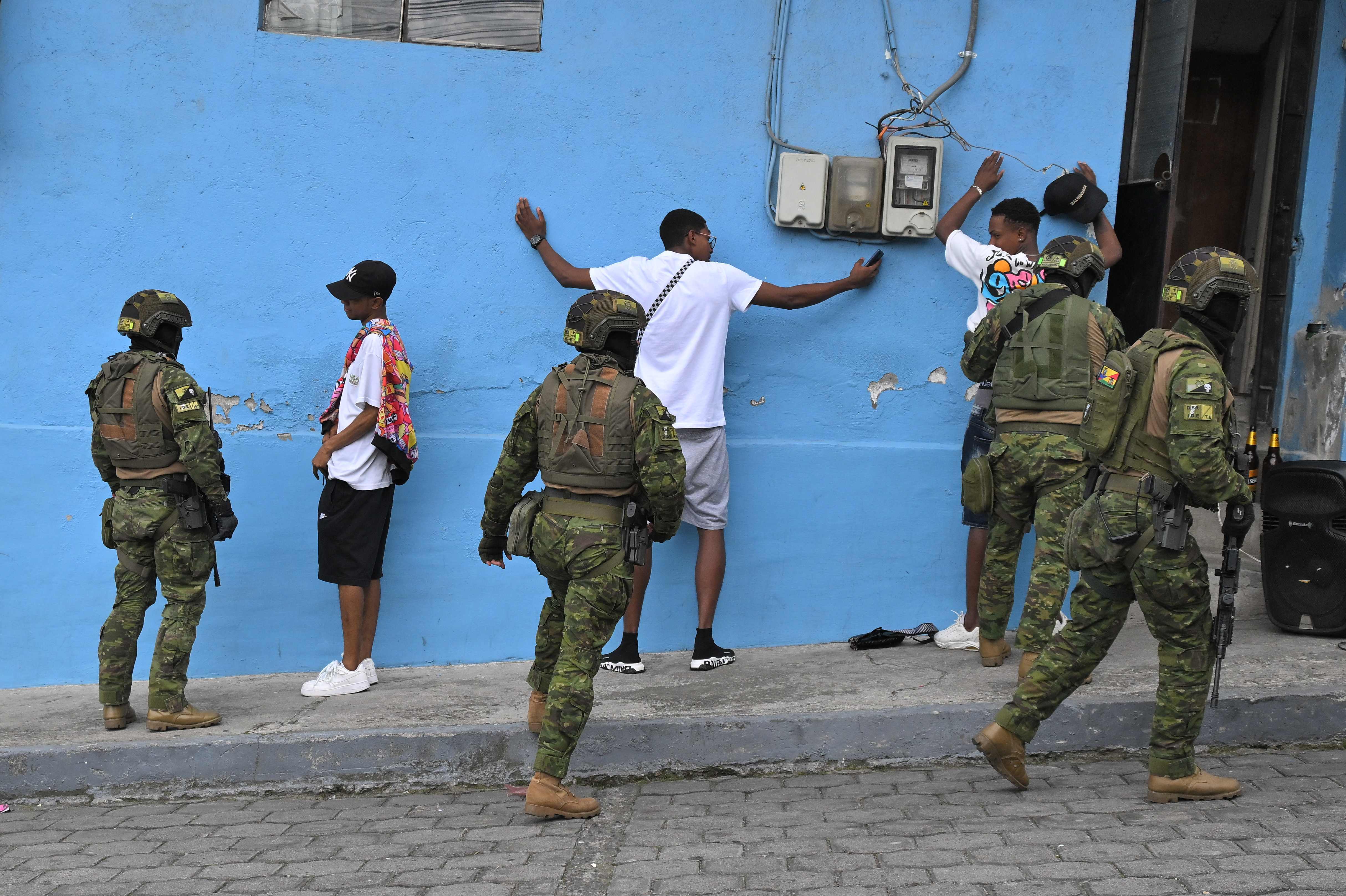 TOPSHOT - Members of the Army's Elite Forces frisk men and check their identities during a patrol in the streets of Moran, a neighbourhood in northern Quito, on January 11, 2024, as Ecuador is in a "state of emergency" since the prison escape of one of the country's most powerful narco bosses. With city streets largely deserted apart from a massive military deployment, Ecuador found itself in a "state of war" Wednesday as drug cartels waged a brutal campaign of kidnappings and attacks in response to a government crackdown. The latest outburst of violence was sparked by the discovery Sunday of the prison escape of one of the country's most powerful narco bosses, Jose Adolfo Macias, known by the alias "Fito." (Photo by AFP)