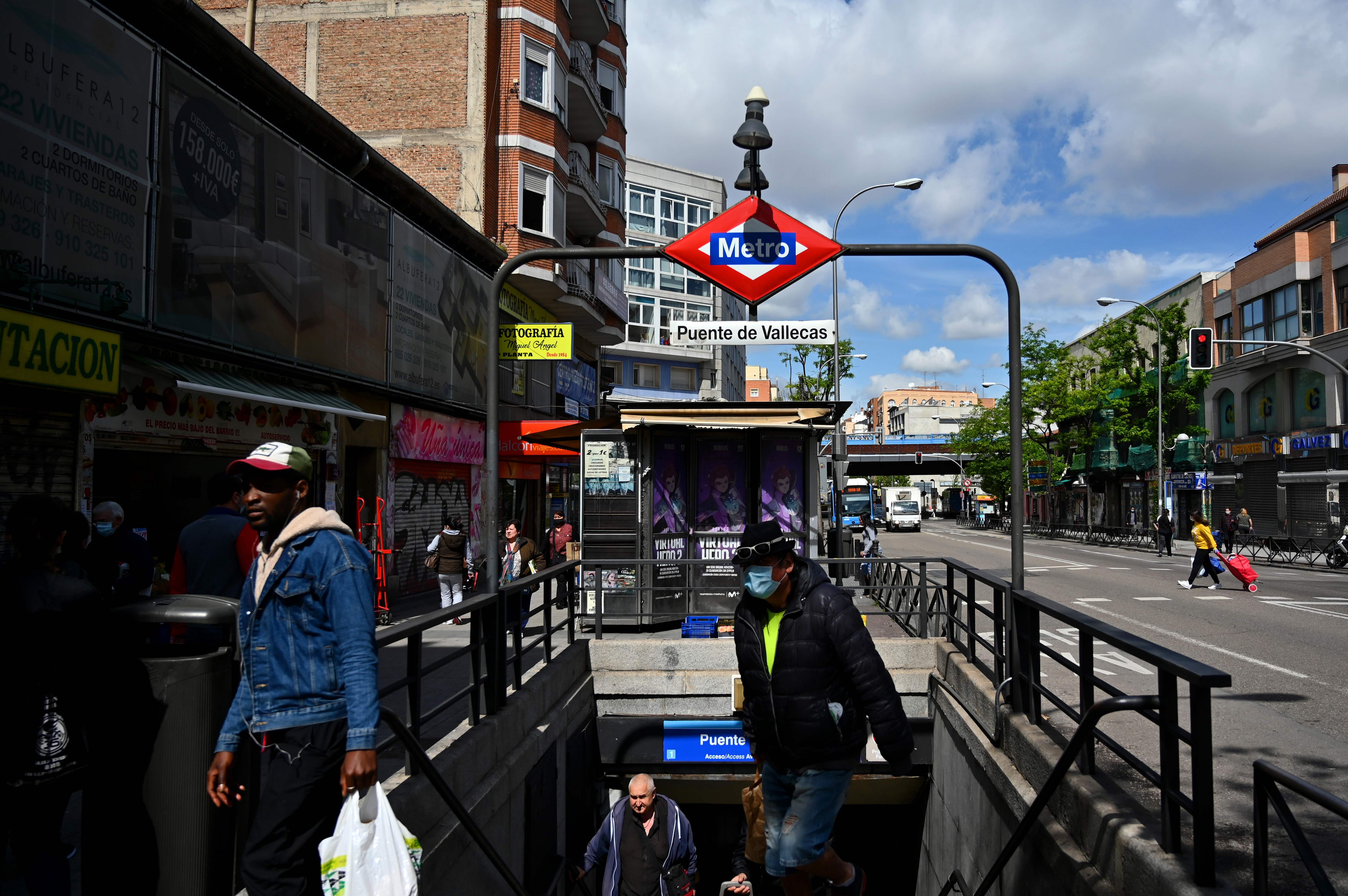 People walk out a metro entrance in Puente de Vallecas, one of the poorest districts in Madrid on April 20, 2020 during a national lockdown to prevent the spread of the COVID-19 disease. - Spain said 399 people died of COVID-19 over the past 24 hours in what was the lowest daily number of deaths in four weeks, the government said. (Photo by Gabriel BOUYS / AFP)