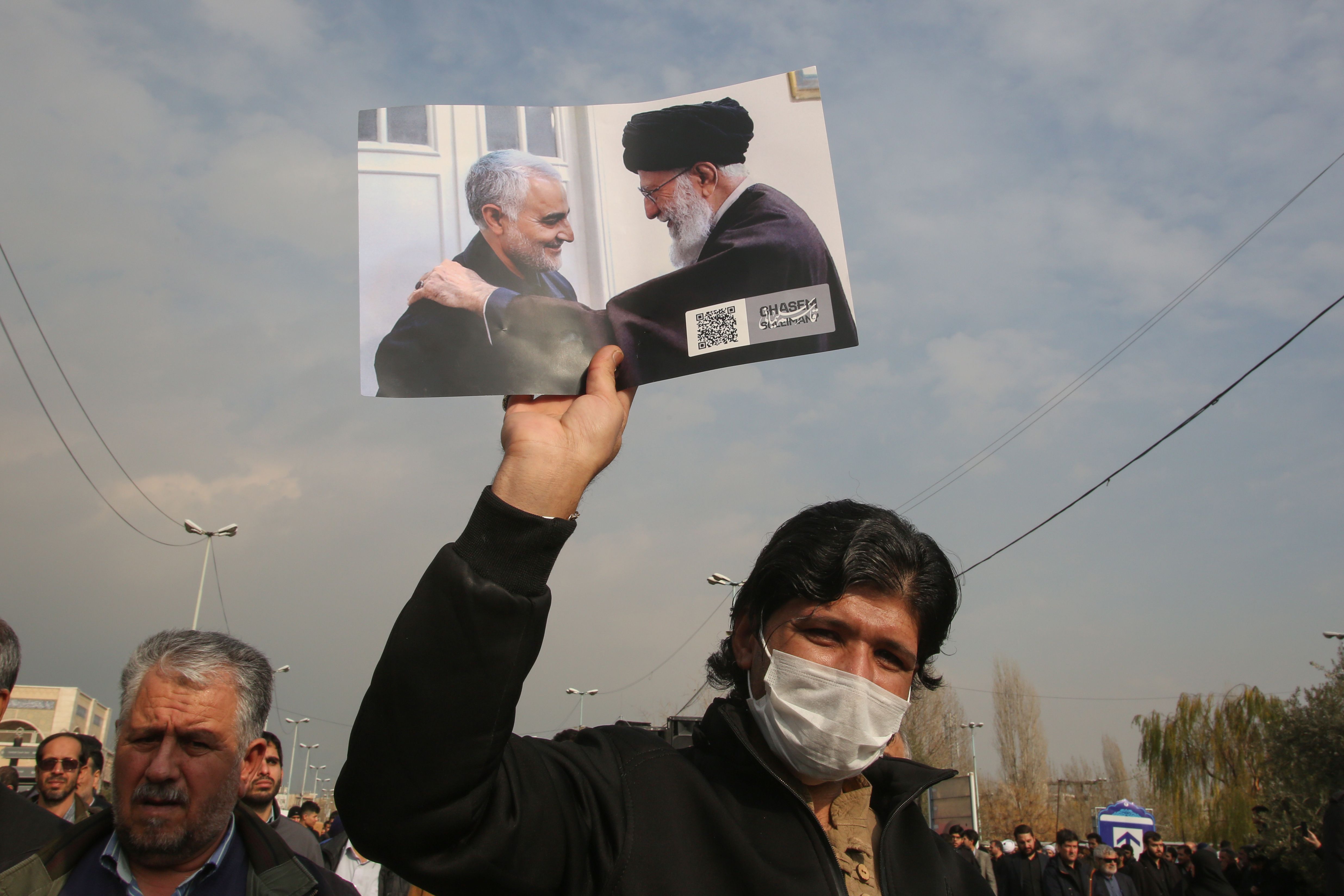 TOPSHOT - A man holds a picture of Iran's supreme leader Ayatollah Ali Khamenei with Iranian Revolutionary Guards Major General Qasem Soleimani (L) during a demonstration in Tehran on January 3, 2020 against the killing of the top commander in a US strike in Baghdad. - Iran warned of "severe revenge" and said arch-enemy the United States bore responsiblity for the consequences after killing one of its top commanders, Qasem Soleimani, in a strike outside Baghdad airport. (Photo by ATTA KENARE / AFP)