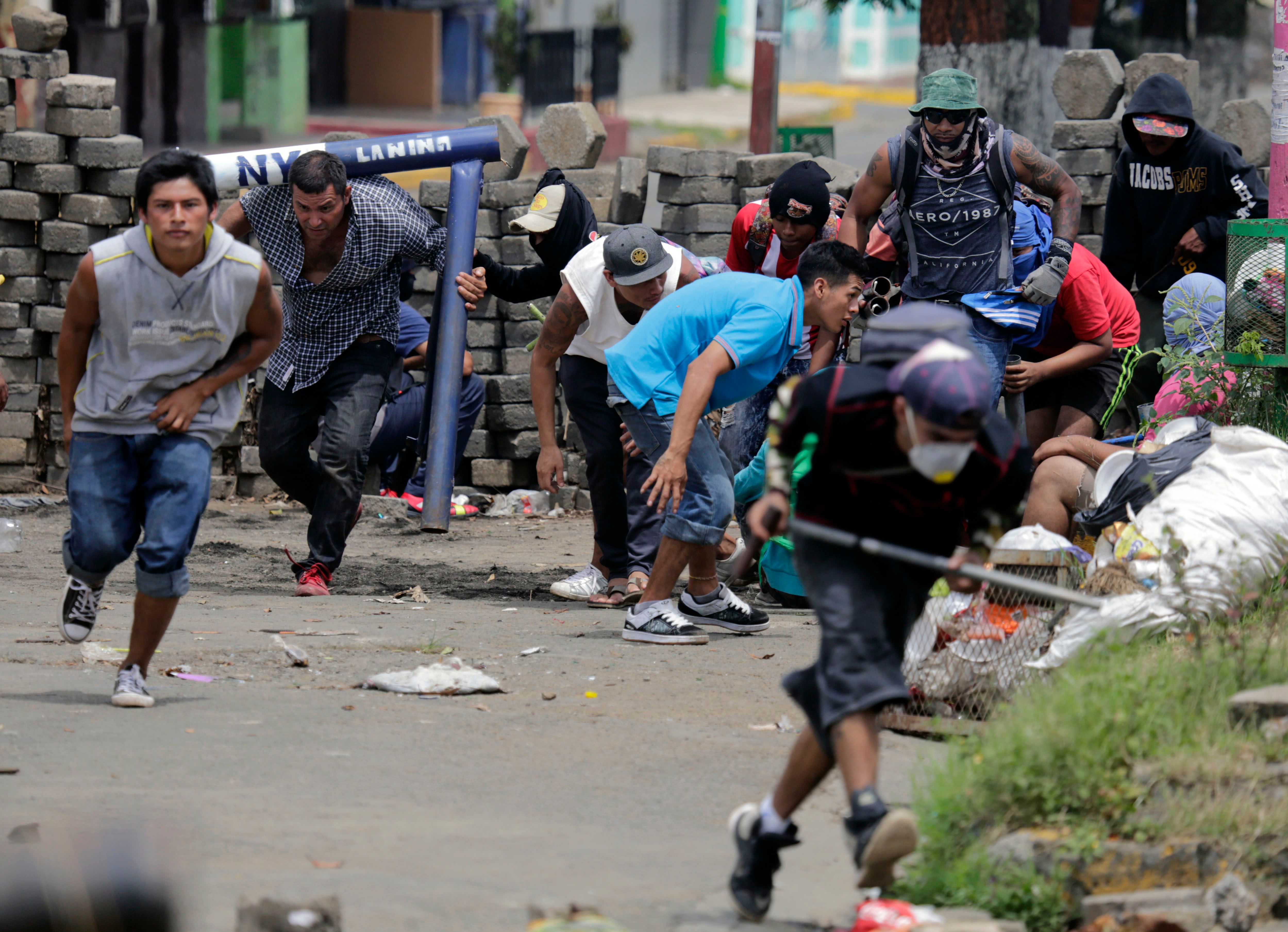 Anti-government demonstrators take cover behind a barricade, during clashes with riot police and members of the Sandinista youth, in Masaya some 35 km from Managua on June 19, 2018.
Nicaraguan police and pro-government paramilitaries moved to reassert control over the city of Masaya by force Tuesday after residents of the opposition bastion declared themselves in rebellion against President Daniel Ortega. / AFP PHOTO / INTI OCON