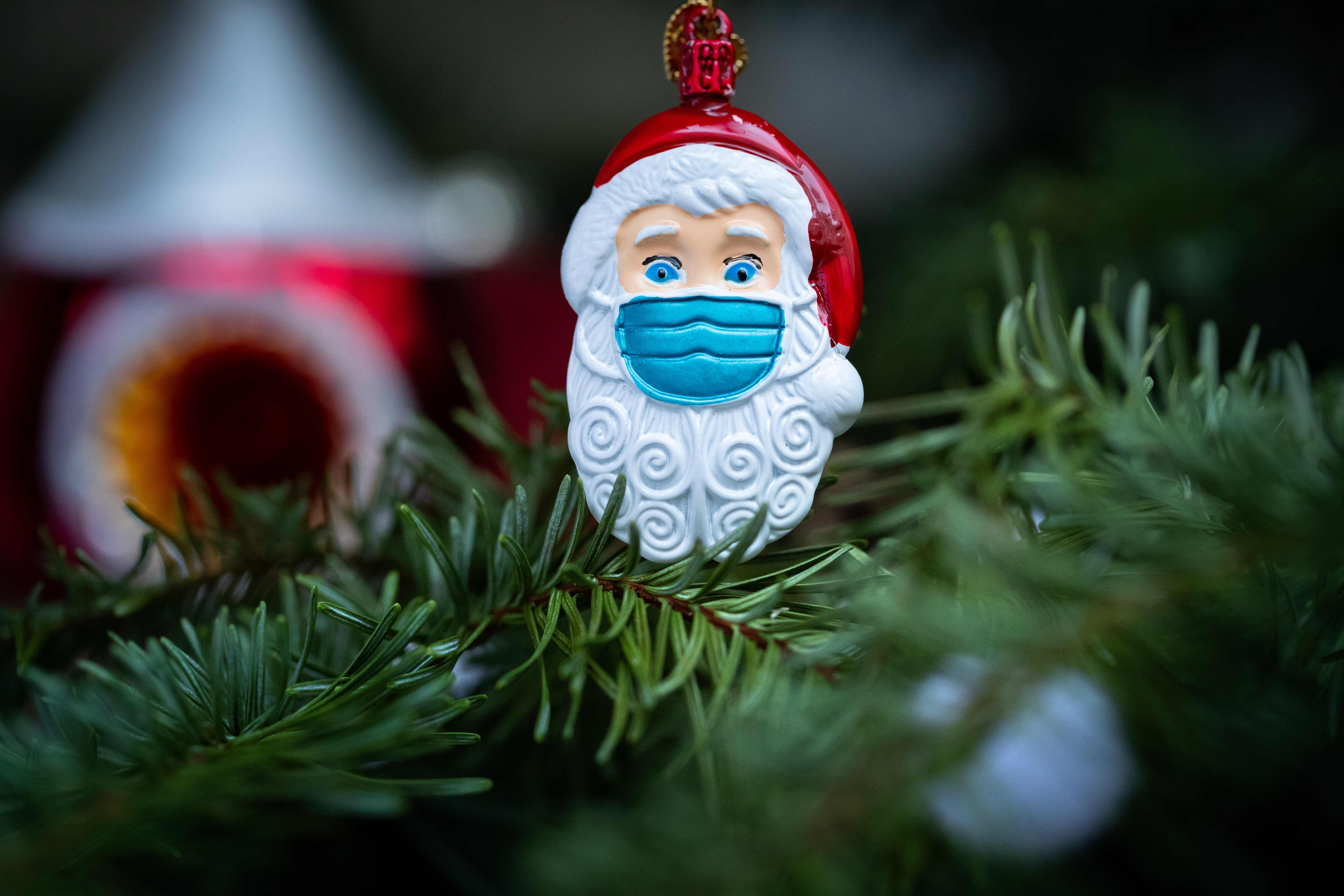 This picture taken in Paris on December 22, 2020 shows a Christmas Santa Claus decoration, with a protective mask. (Photo by JOEL SAGET / AFP)