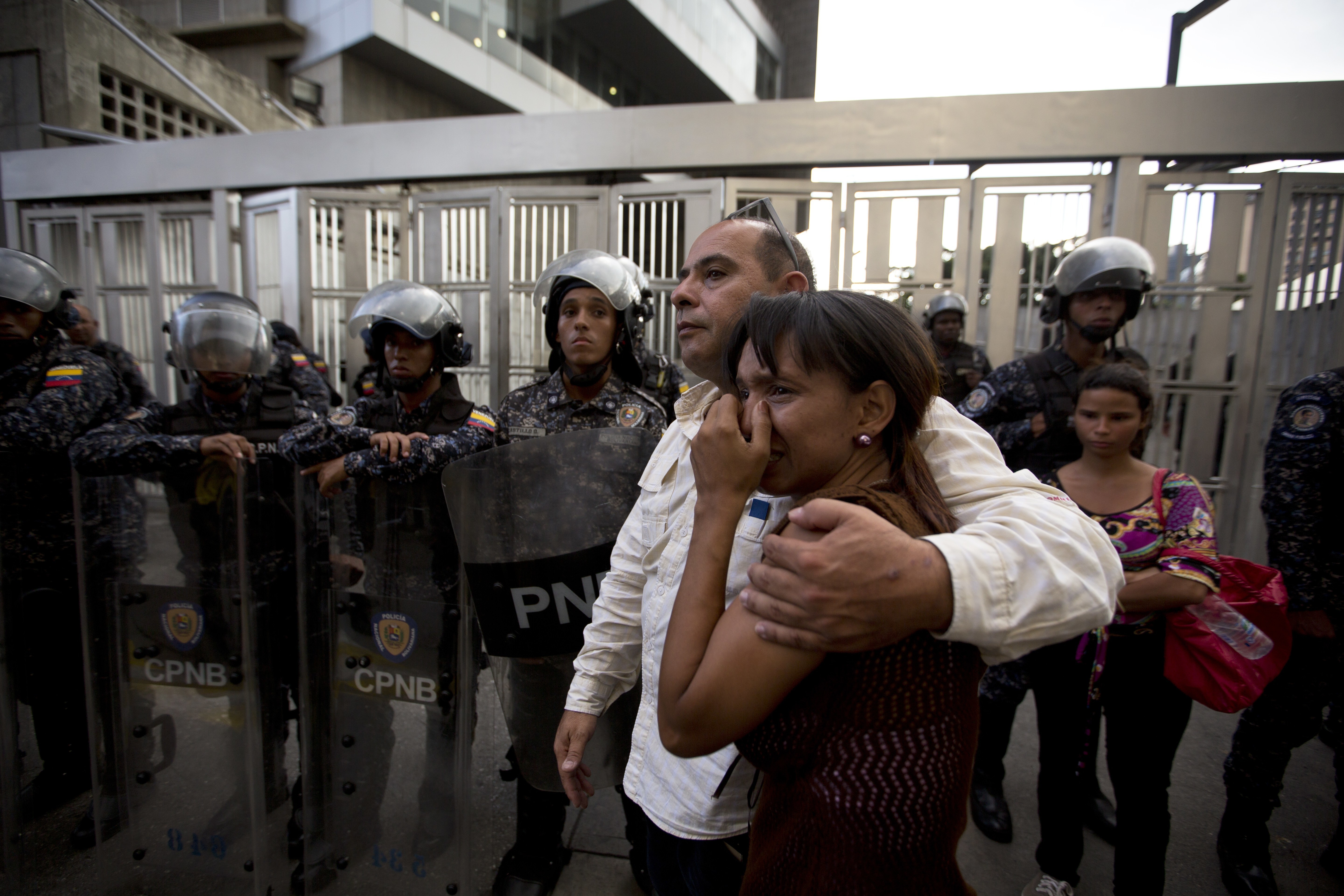 Staff members of jailed councilman Alberto Alban Salazar embrace outside the Bolivarian National Security Service (SEBIN) headquarters in Caracas, Venezuela, Monday, Oct. 8, 2018. Venezuela's Attorney General Tarek William Saab said Monday that Salazar, who was arrested on suspicion of involvement in a failed assassination attempt on President Nicolas Maduro, has died of suicide while jailed at SEBIN. (AP Photo/Fernando Llano)