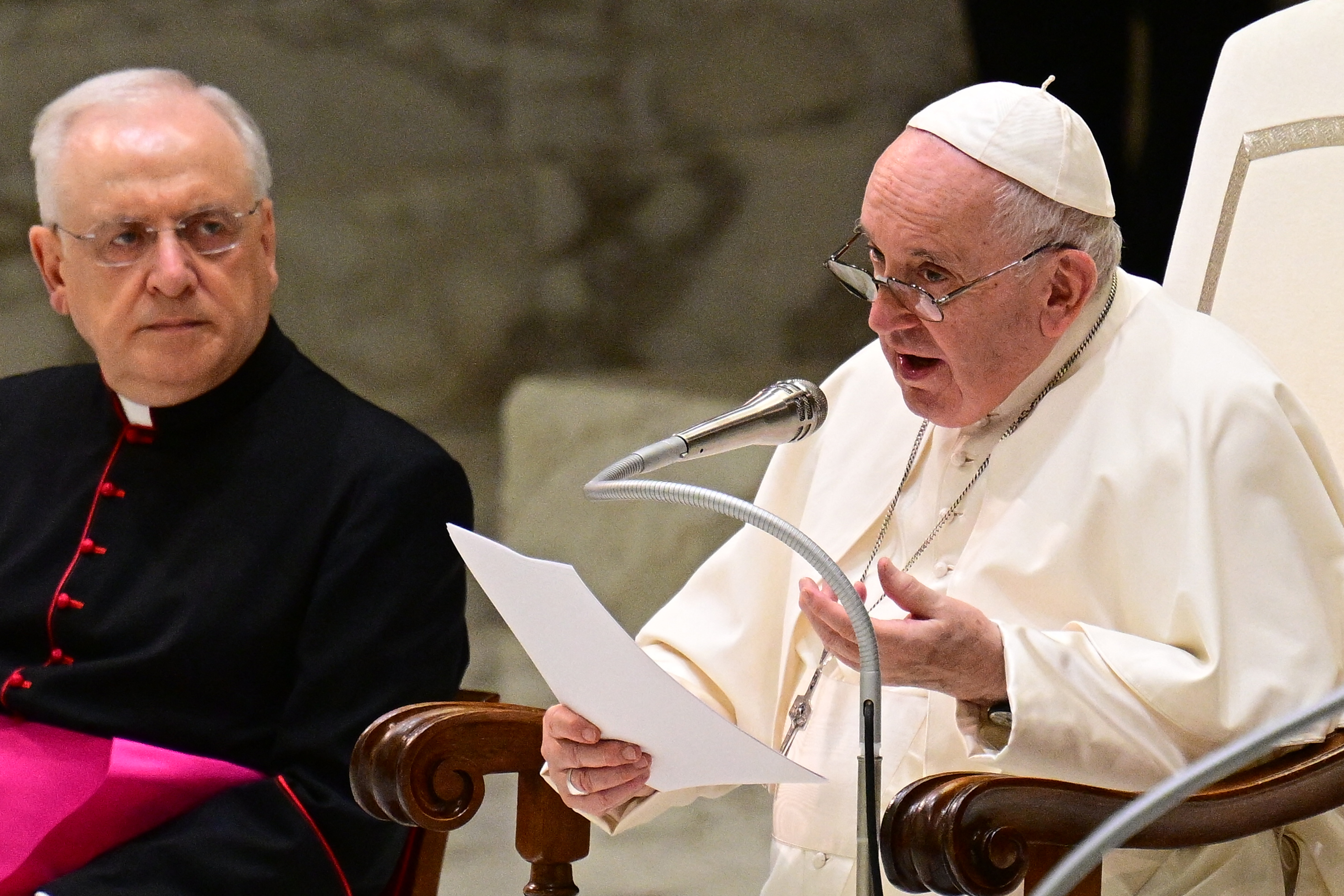 Pope Francis, assisted by Prefect of the Pontifical House, Monsignor Leonardo Sapienza (L), speaks during the weekly general audience on August 17, 2022 at Paul-VI hall in The Vatican. (Photo by Vincenzo PINTO / AFP)