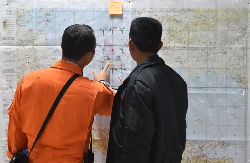 Dos integrantes de la Fuerza Aérea de Indonesia observaron ayer un mapa del área de destino que fue cubierta por un avión Hércules C-130 sobre el mar de Java, durante las operaciones de búsqueda y rescate de desaparecidos del vuelo AirAsia QZ8501. Este se perdió de los radares el domingo, cuando iba rumbo a Singapur. | AFP