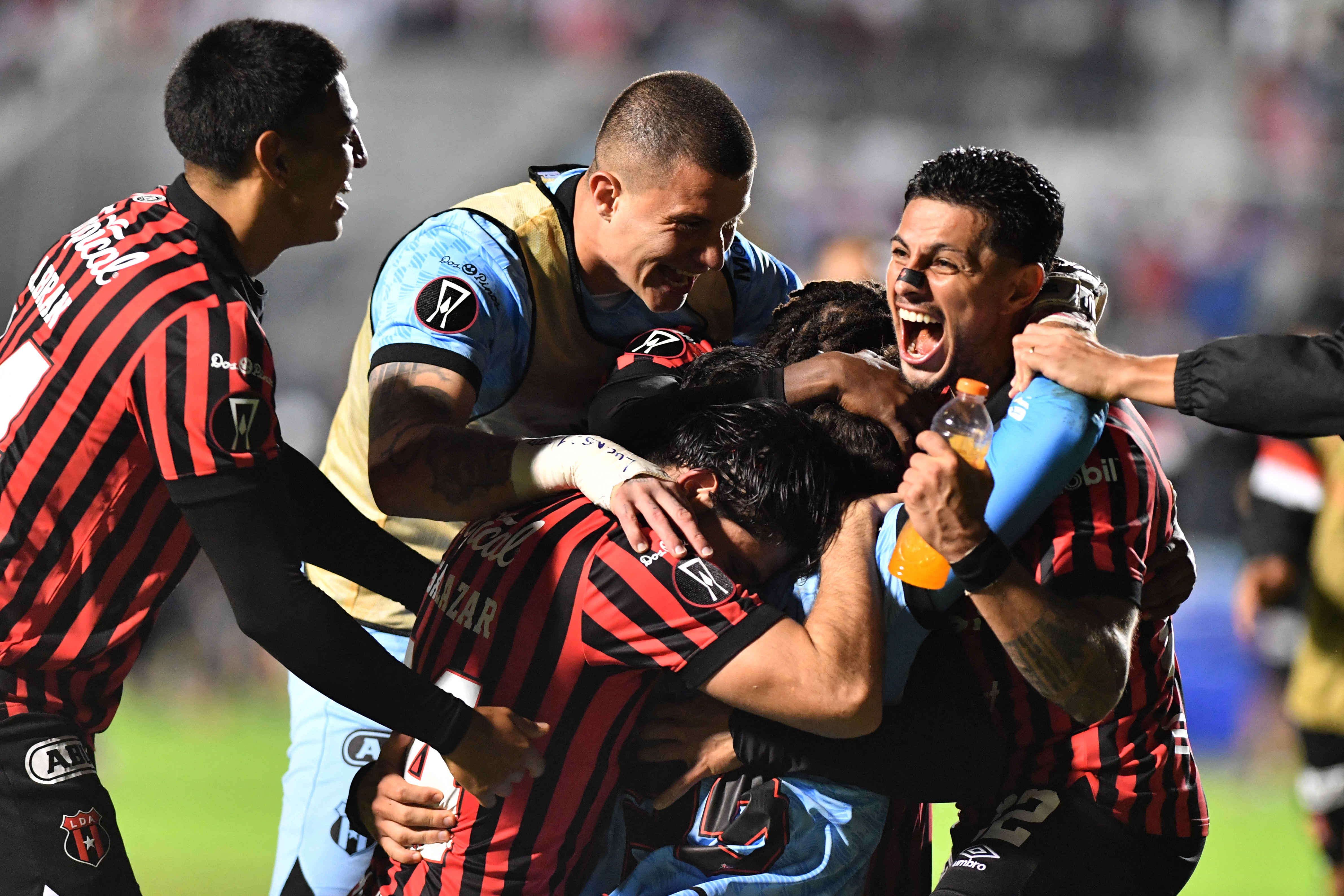 Alajuelense's Uruguayan goalkeeper #23 Washington Ortega (C) celebrates with teammates after winning the penalty shootout and the second leg of the CONCACAF Central American Cup semifinal football match between Honduras's Olimpia and Costa Rica's Alajuelense at the National Stadium Jose de la Paz Herrera in Tegucigalpa on October 30, 2025. (Photo by Orlando SIERRA / AFP)
