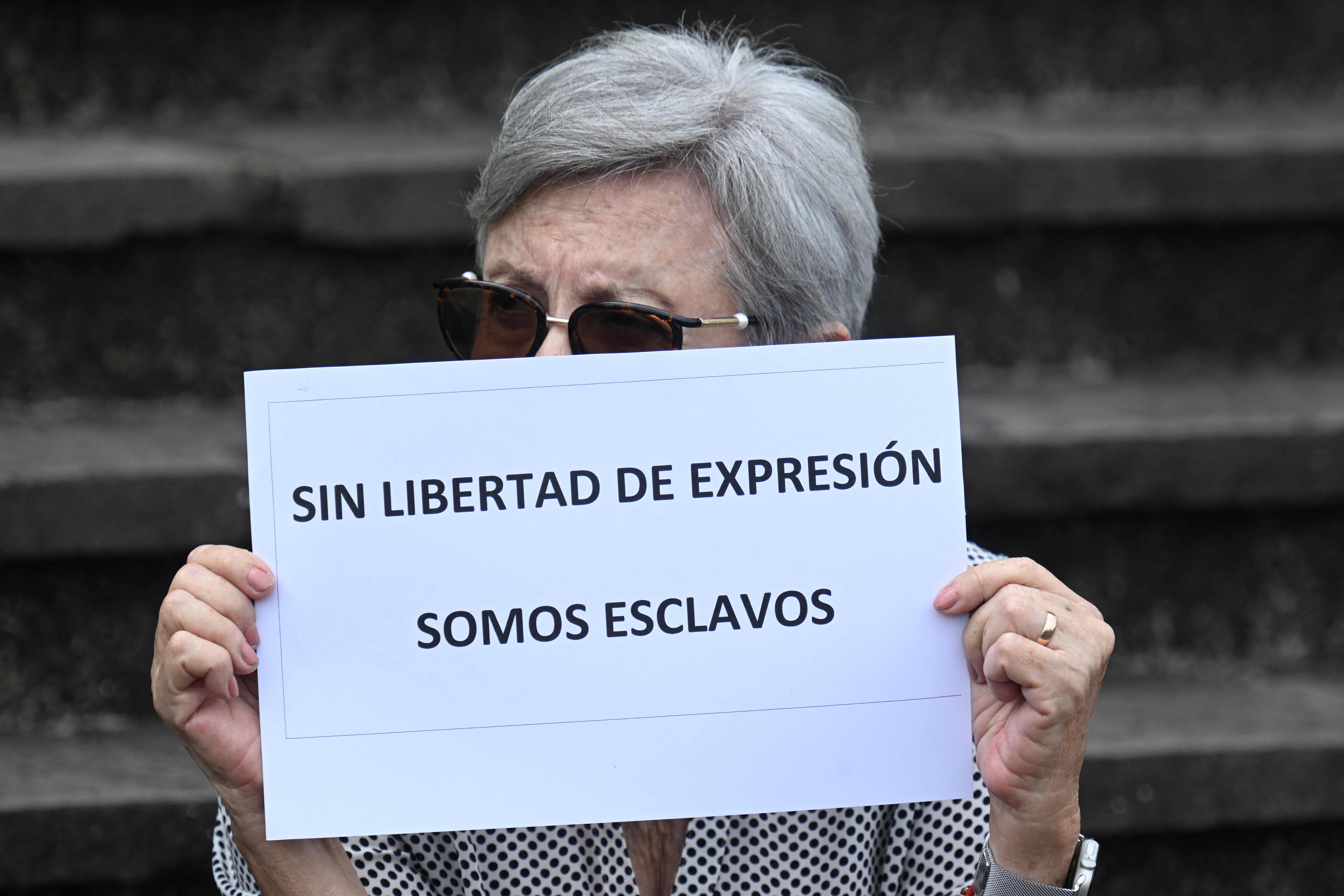 A woman holds a sign that reads "Without freedom of speech we are slaves" during a demonstration against the closure of the "El Periodico" newspaper outside the Justice Palace in Guatemala City on May 15, 2023. An investigative newspaper in Guatemala that published reports on government corruption announced on Friday it was closing due to "criminal persecution and economic pressure." In March, a judge opened an investigation into journalists and columnists working for El Periodico. The newspaper's founder, Jose Ruben Zamora, who has won several international press awards for his paper's investigative journalism, was arrested last year and accused of money laundering and blackmail. (Photo by Johan ORDONEZ / AFP)
