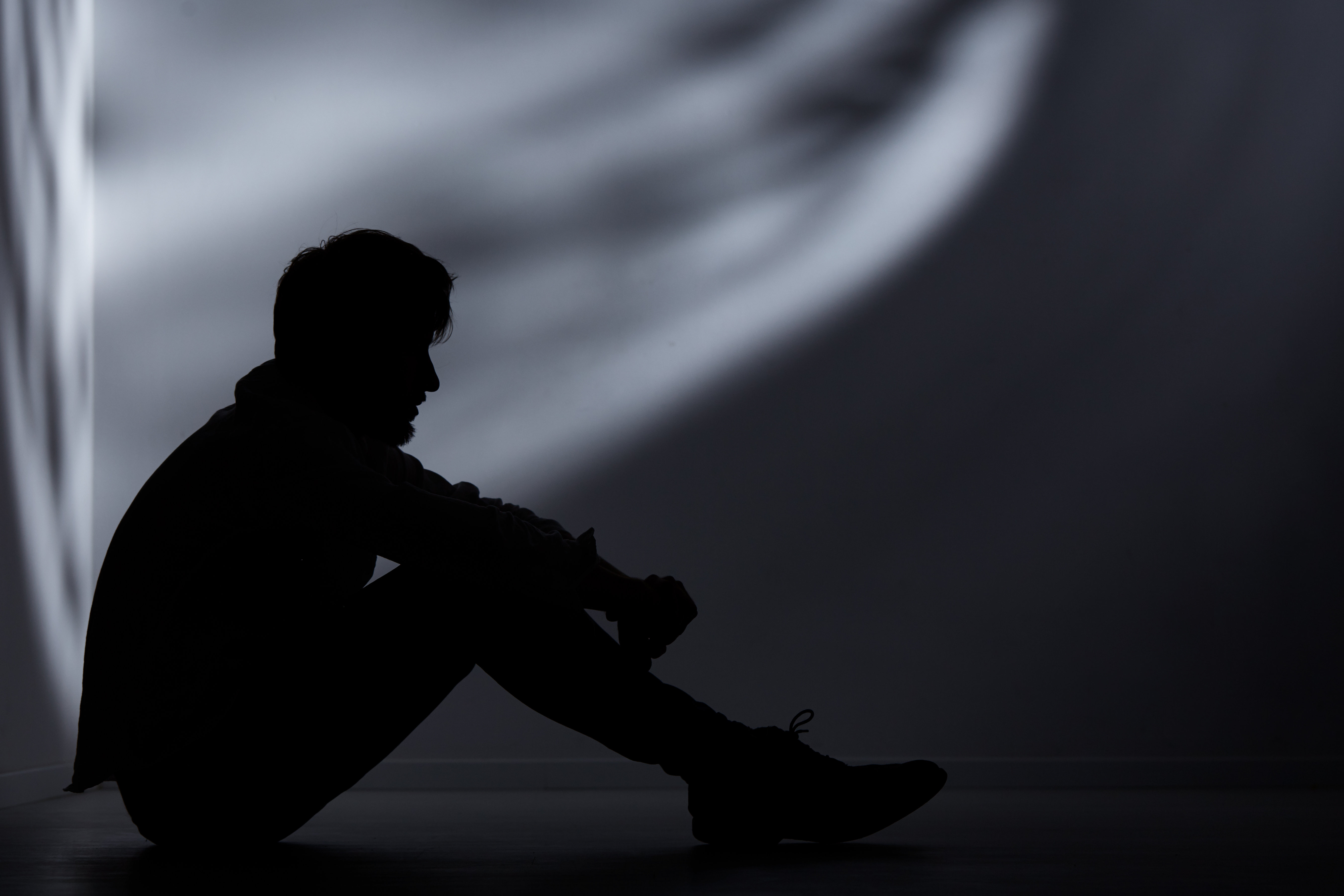 Abandoned man sitting on floor in dark room