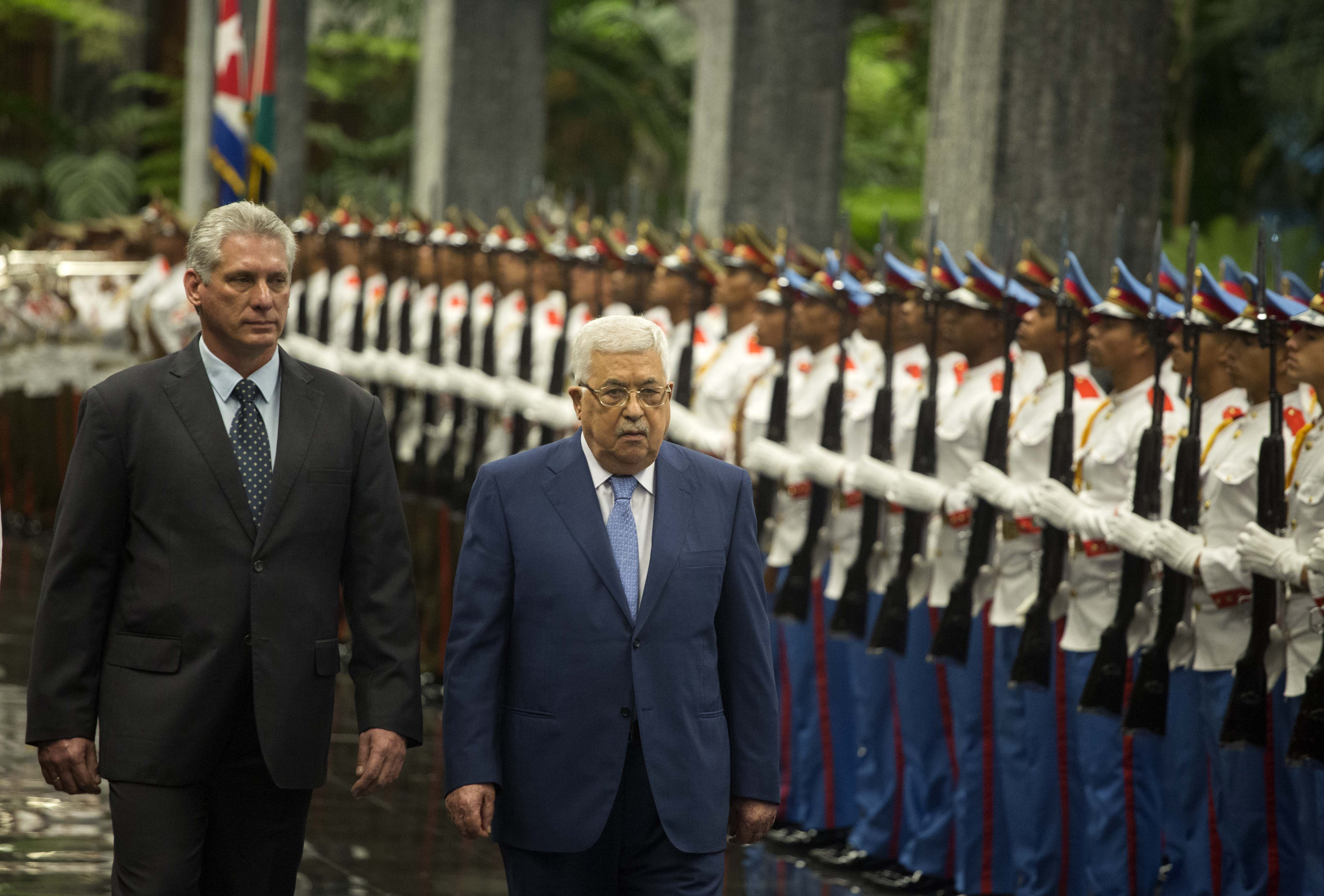 Palestinian President Mahmoud Abbas, center, and Cuba's President Miguel Diaz-Canel review an honor guard at the Revolution Palace in Havana, Cuba, Friday, May 11, 2018. (AP Photo/Desmond Boylan)