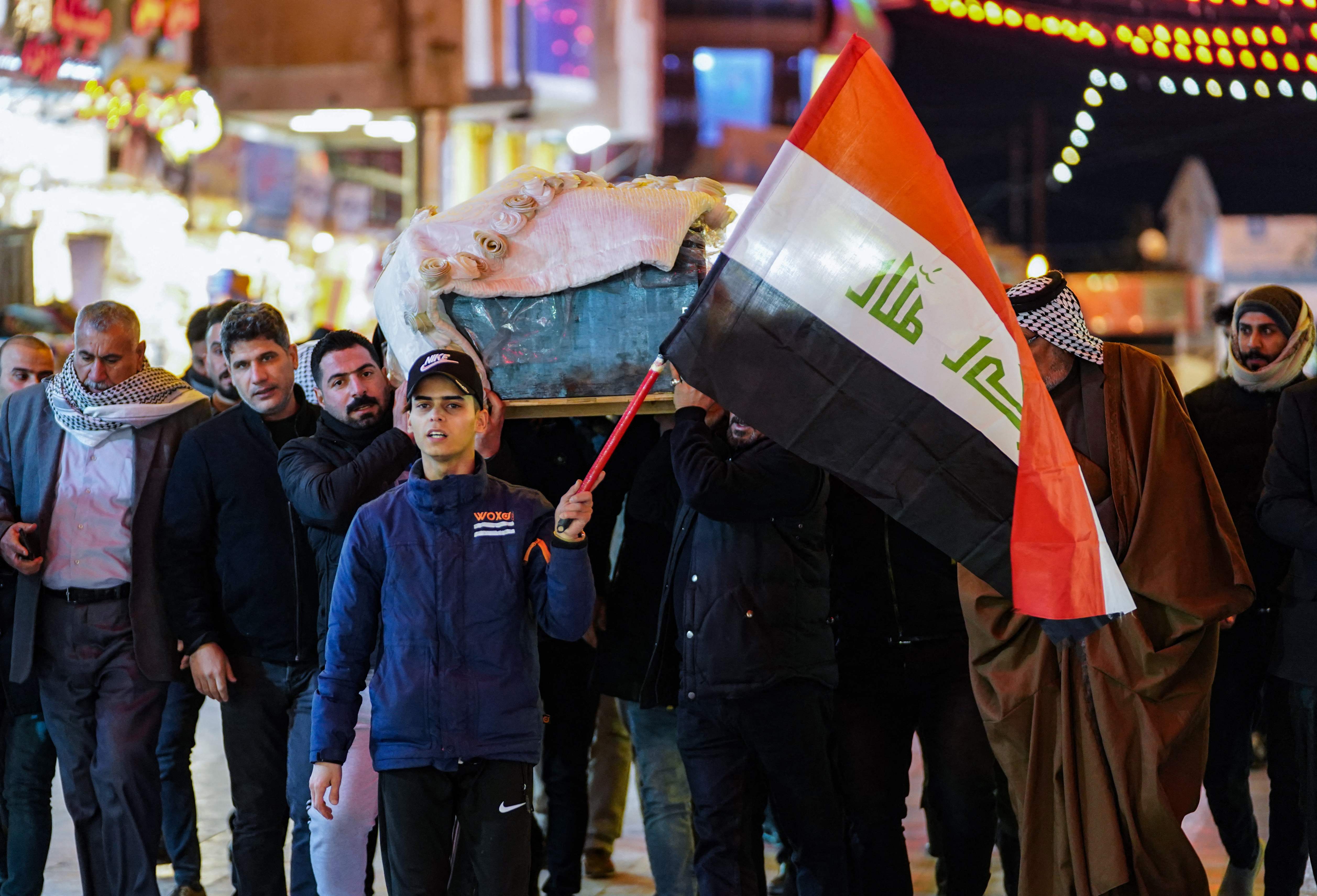 Mourners carry the casket of one of eleven Iraqi soldiers, killed in an overnight attack by the Islamic State (IS) group against a base in eastern Iraq, through a street in the central holy shrine city of Najaf, on January 21, 2022. - The extremist group took over large swathes of Iraq and neighbouring Syria in 2014, declaring itself a new "caliphate" for Muslims, before Baghdad declared victory in late 2017 after a grinding national campaign. (Photo by Ali NAJAFI / AFP)