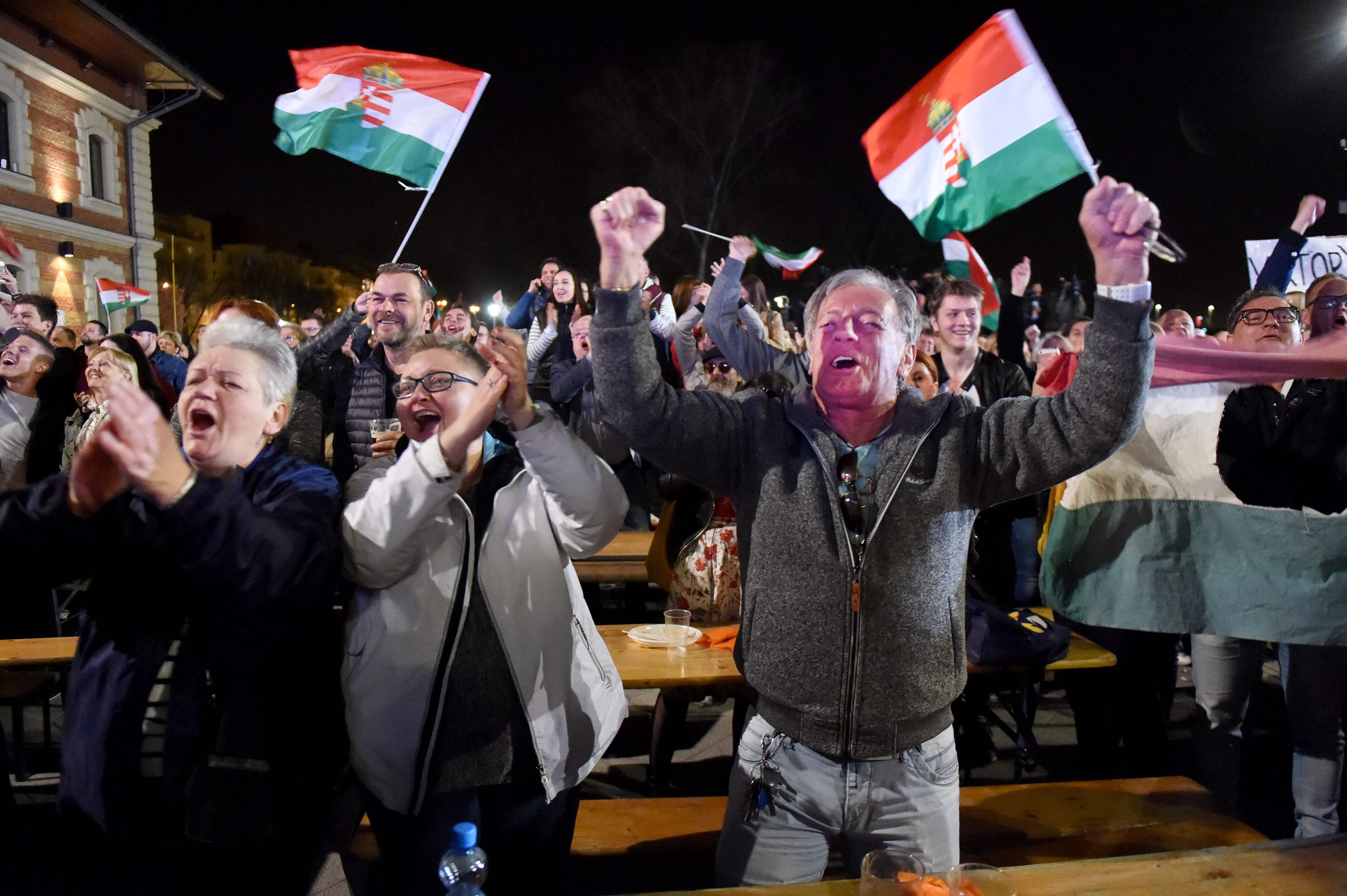 Supporters of the FIDESZ party react as Hungarian Prime Minister Viktor Orban (not pictured) celebrates from the podium of the banks of the Danube River after winning the parliamentary election on April 8, 2018 in Budapest. / AFP PHOTO / ATTILA KISBENEDEK