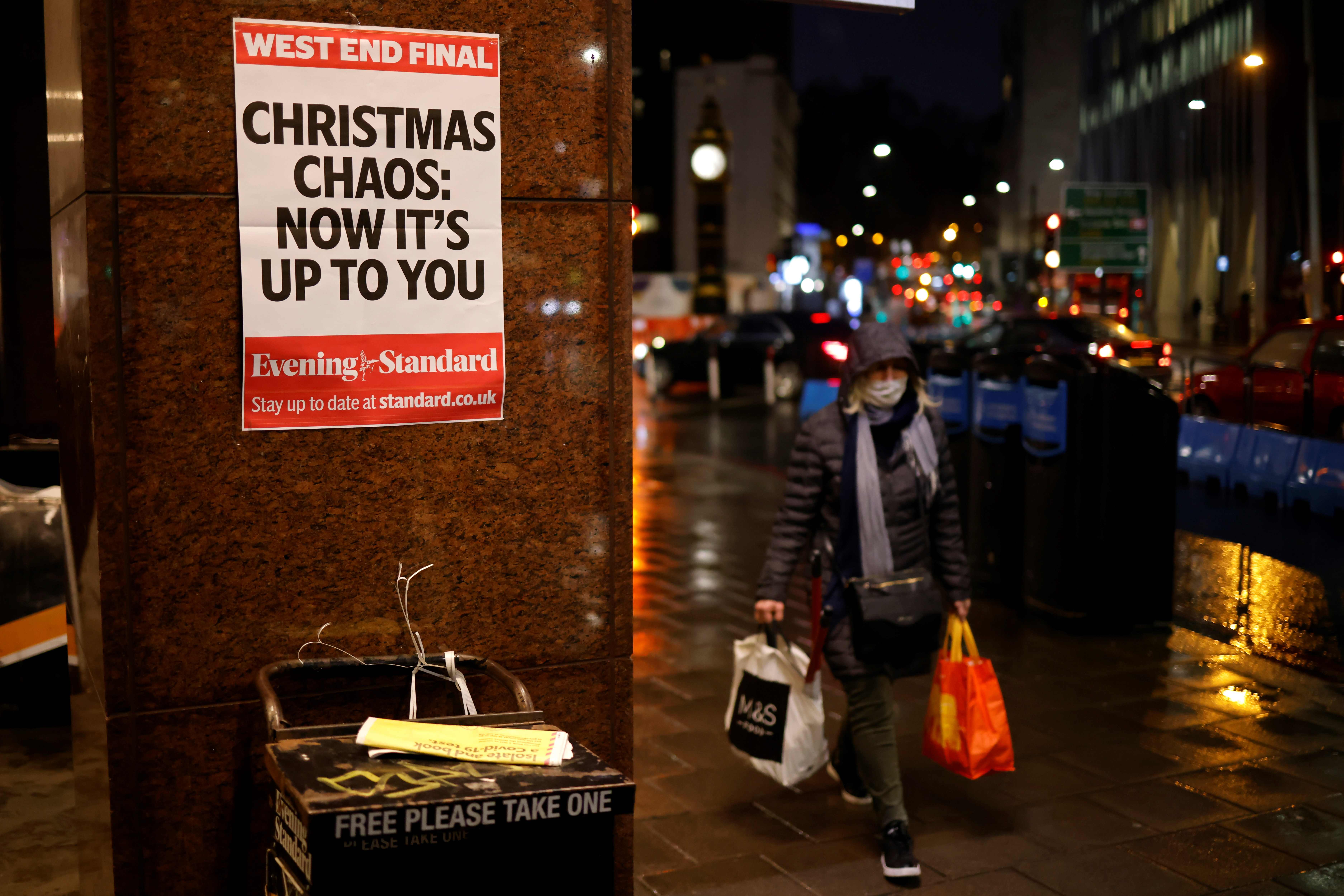 A shopper wears a facemask as she walks past an Evening Standard newspaper stand at Victoria Station in central London on December 16, 2020, as new guidance on Christmas during the novel coronavirus COVID-19 pandemic was announced by the government. - Prime Minister Boris Johnson resisted calls to tighten coronavirus restrictions over Christmas, as London faced stricter measures and concern mounted about case numbers. (Photo by Tolga Akmen / AFP)