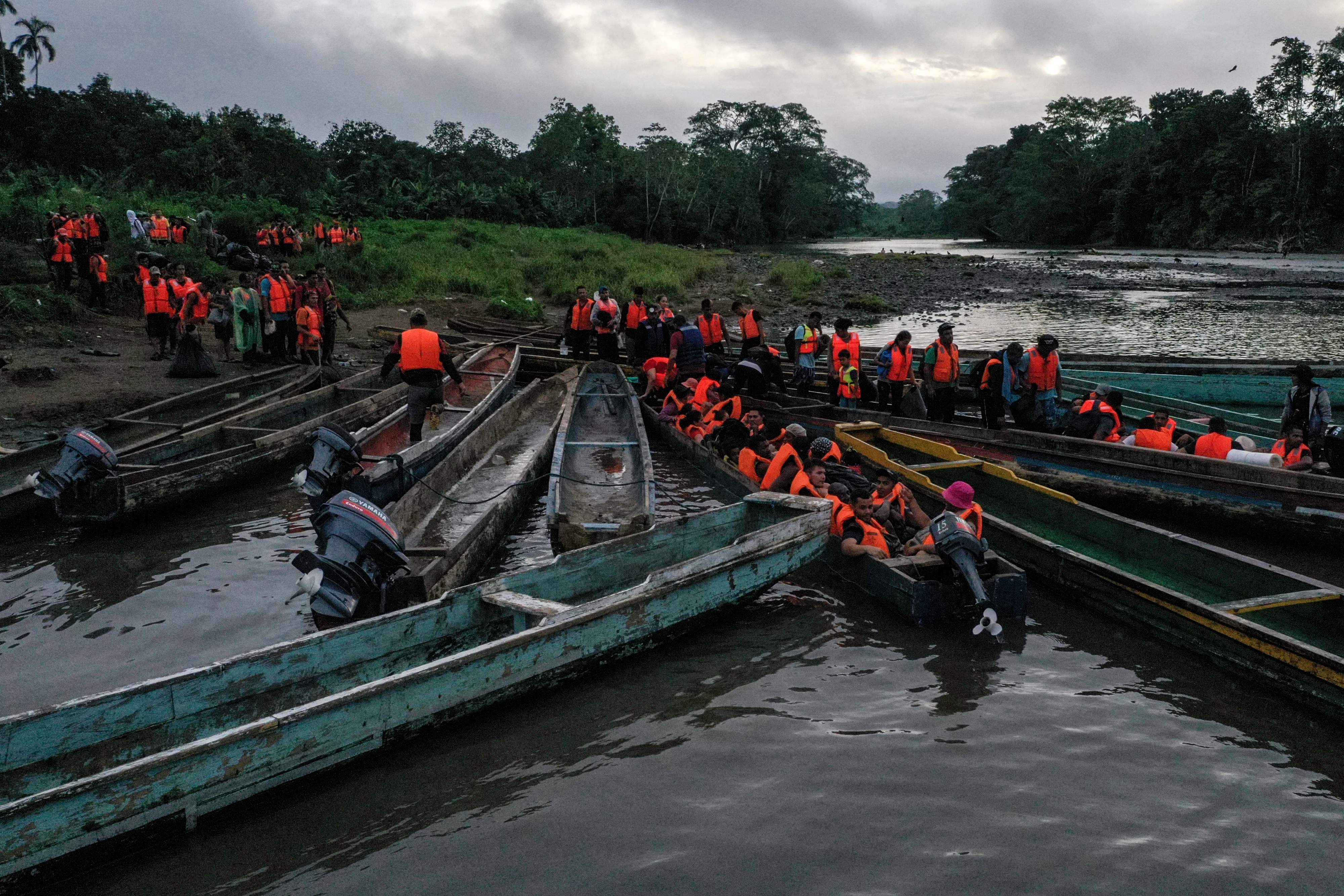 (FILES) Migrants queue to be transported from Canaan Membrillo village to the Migrants Reception Station in Meteti, Darien Province, Panama, on October 13, 2022. Halfway into 2023, nearly a quarter million migrants have crossed the Darien Gap, the dense jungle separating Panama and Colombia, already breaking last year's record, Panama's government said on July 31, 2023. The Darien Gap, 165 miles (265 kilometres) long, has become a corridor from South America for migrants heading to the United States via Central America, despite its dangers. (Photo by Luis ACOSTA / AFP)