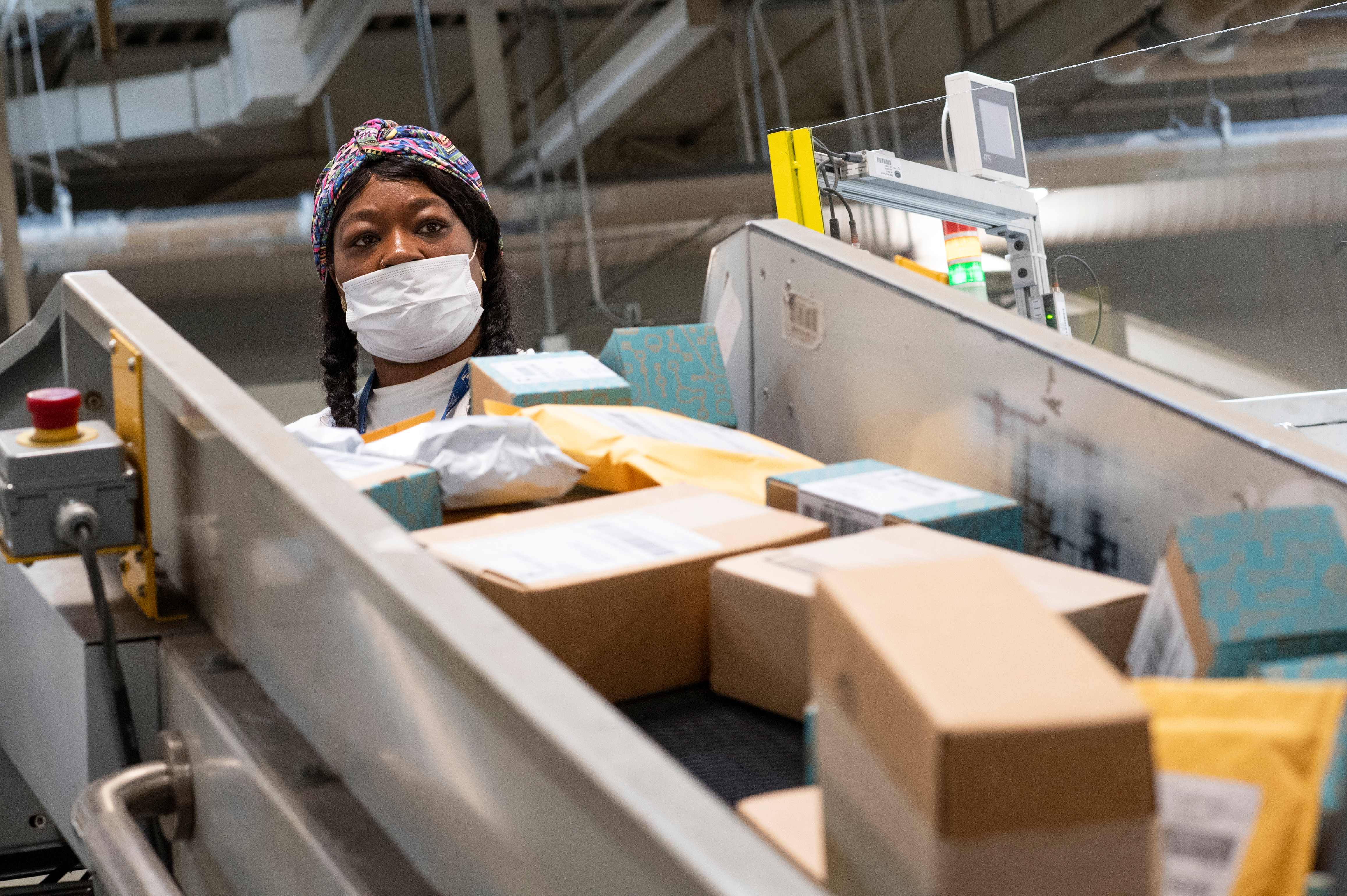 (FILES) In this file photo taken on April 30, 2020, a postal worker sort mail at a Los Angeles, California, facility. - The US Postal Service is popularly known for delivering mail despite snow, rain or heat, but it faces a new foe in President Donald Trump. Ahead of the November 3 elections in which millions of voters are expected to cast ballots by mail due to the threat of the coronavirus, Trump has leveled an unprecedented attack at the USPS, opposing efforts to give the cash-strapped agency more money even as changes at the agency have caused widespread delays in delivering letters and packages. (Photo by VALERIE MACON / AFP)