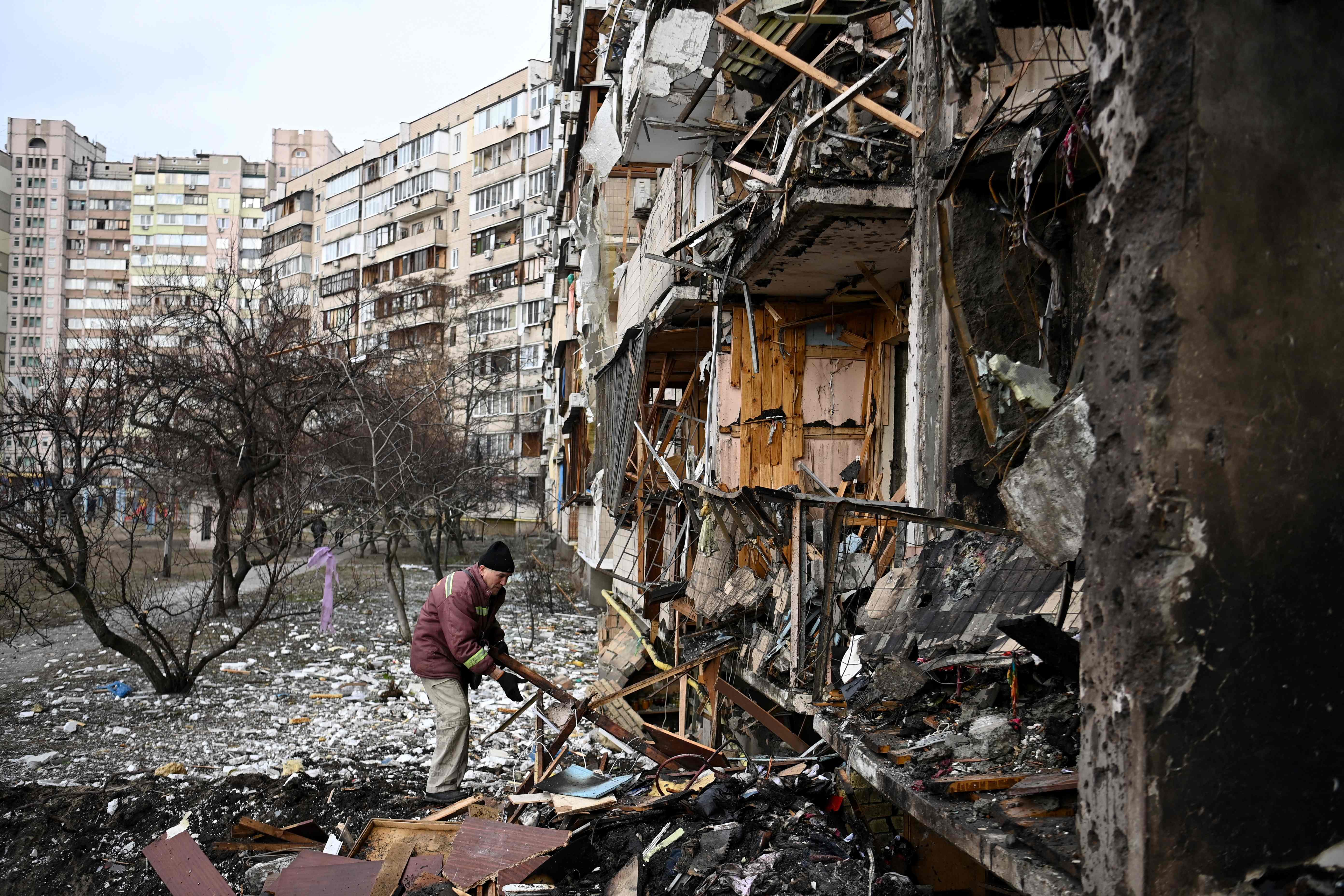 TOPSHOT - A man clears debris at a damaged residential building at Koshytsa Street, a suburb of the Ukrainian capital Kyiv, where a military shell allegedly hit, on February 25, 2022. - Russian forces reached the outskirts of Kyiv on Friday as Ukrainian President Volodymyr Zelensky said the invading troops were targeting civilians and explosions could be heard in the besieged capital. Pre-dawn blasts in Kyiv set off a second day of violence after Russian President Vladimir Putin defied Western warnings to unleash a full-scale ground invasion and air assault on Thursday that quickly claimed dozens of lives and displaced at least 100,000 people. (Photo by Daniel LEAL / AFP)