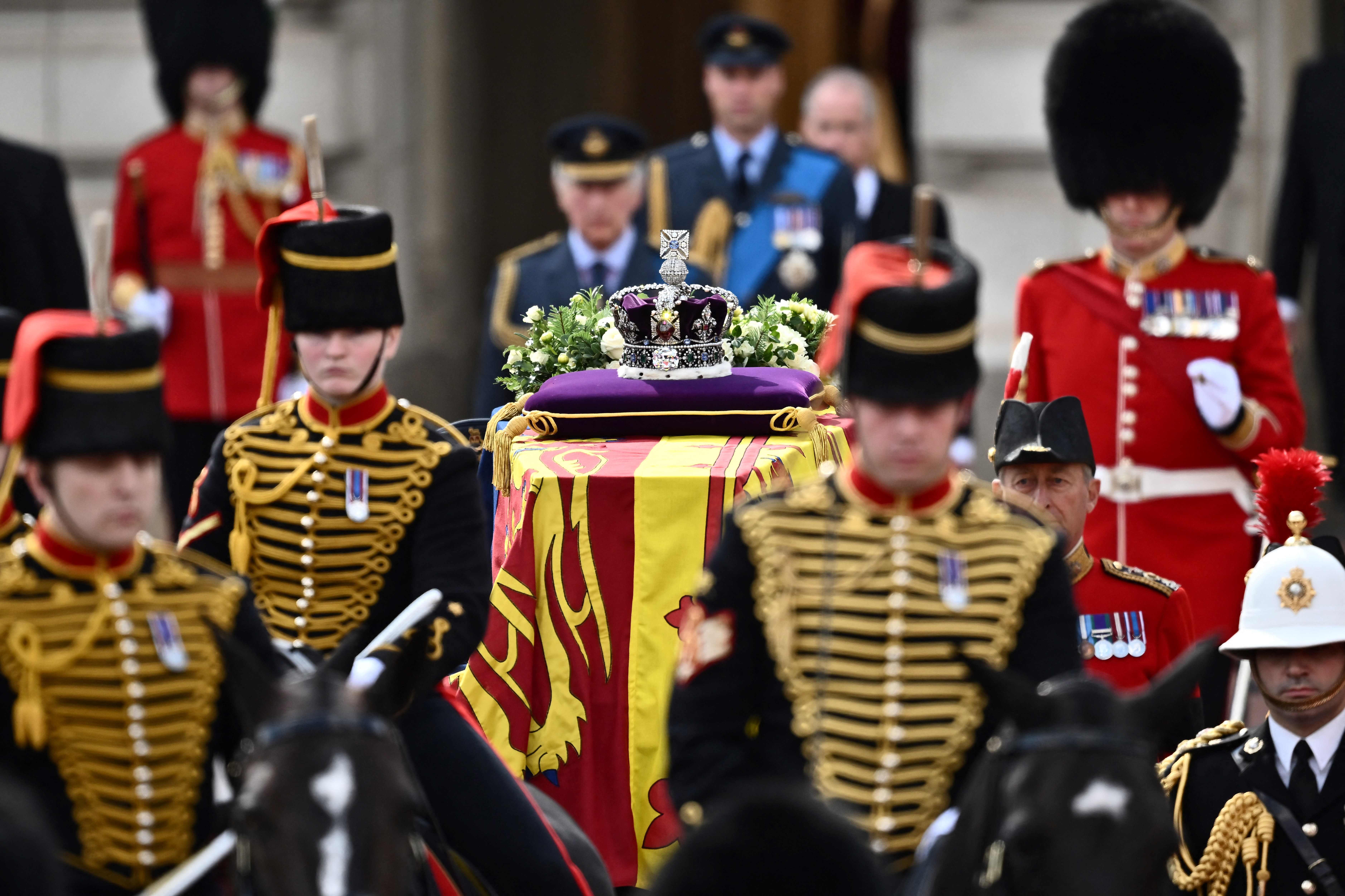 TOPSHOT - The coffin of Queen Elizabeth II, adorned with a Royal Standard and the Imperial State Crown and pulled by a Gun Carriage of The King's Troop Royal Horse Artillery, is pictured during a procession from Buckingham Palace to the Palace of Westminster, in London on September 14, 2022. - Queen Elizabeth II will lie in state in Westminster Hall inside the Palace of Westminster, from Wednesday until a few hours before her funeral on Monday, with huge queues expected to file past her coffin to pay their respects. (Photo by Marco BERTORELLO / AFP)
