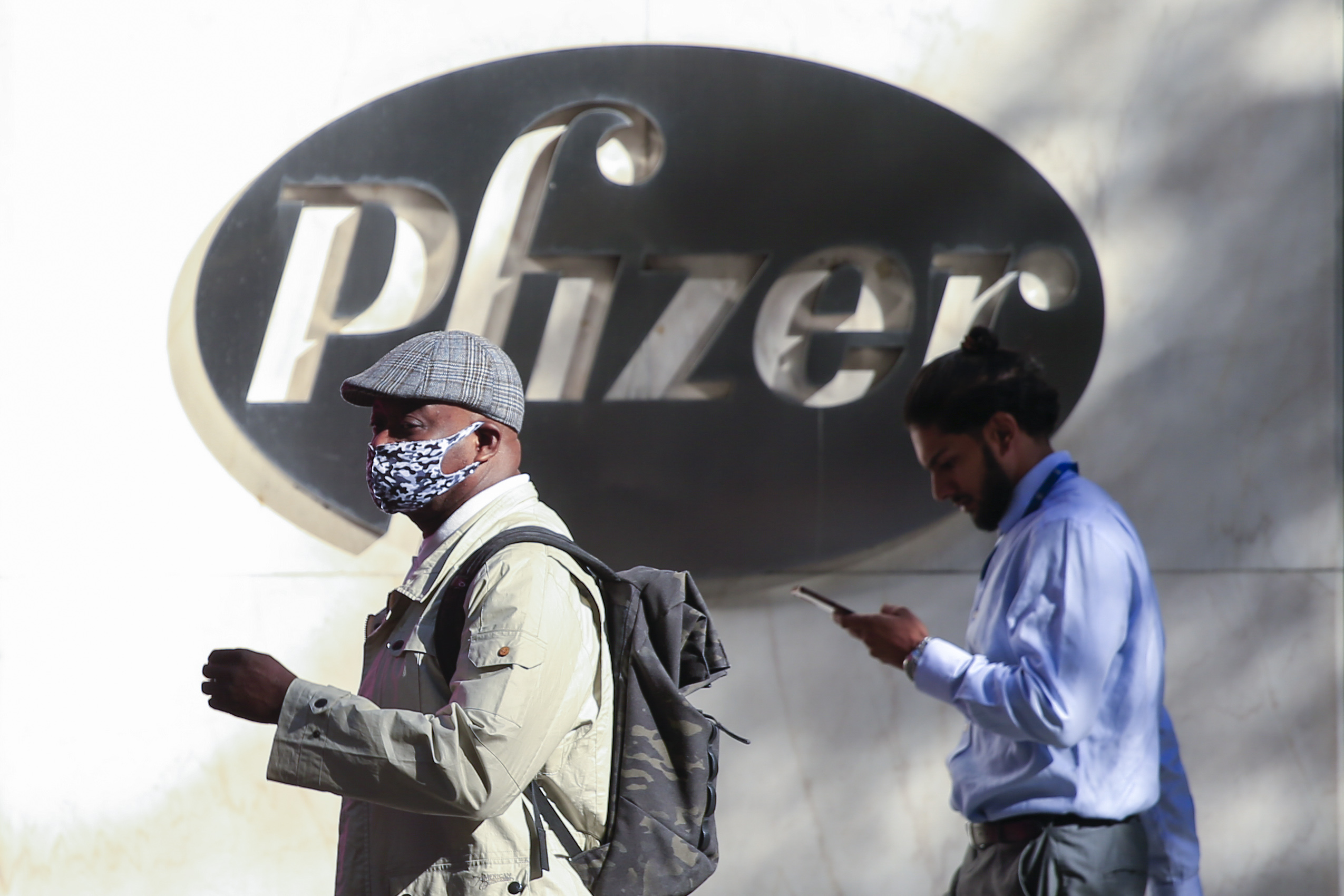 People walk by the Pfizer world headquarters in New York on November 9, 2020. - Pfizer stock surged higher on November 9, 2020 prior to the opening of Wall Street trading after the company announced its vaccine is "90 percent effective" against Covid-19 infections. The news cheered markets worldwide, especially as coronavirus cases are spiking, forcing millions of people back into lockdown. (Photo by Kena Betancur / AFP)