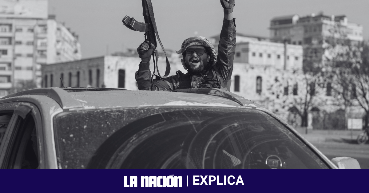 Combatiente rebelde islamista levantando su arma y celebrando desde un vehículo en las calles de Hama, Siria.