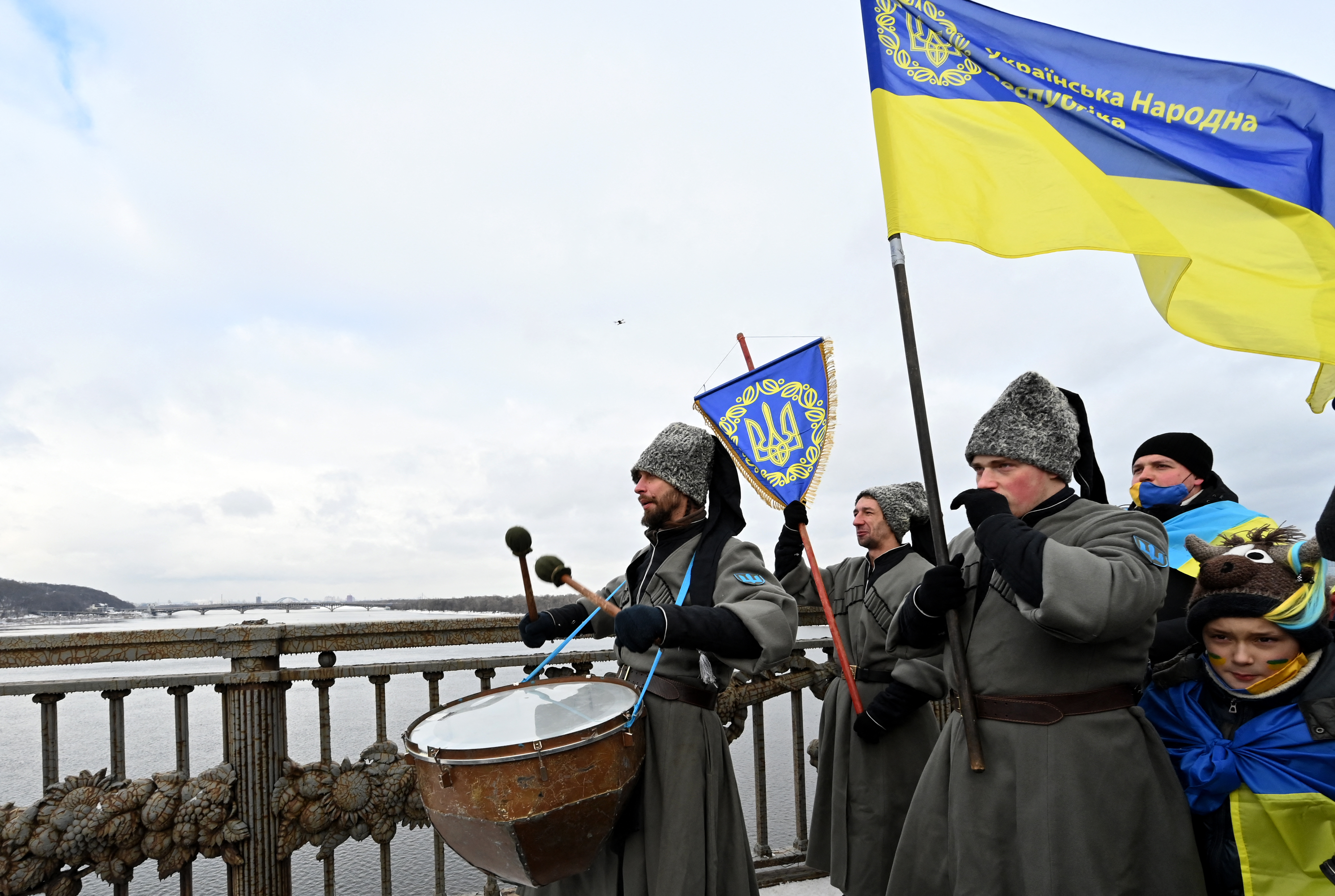 People, wearing the historic military uniforms of the People's Republic of Ukraine, form a symbolic human chain on a bridge across the Dnieper river in Kyiv, to mark the "Day of Unity" which celebrate the 103rd anniversary of the unification of eastern and western Ukraine on January 22, 2022. (Photo by Sergei SUPINSKY / AFP)