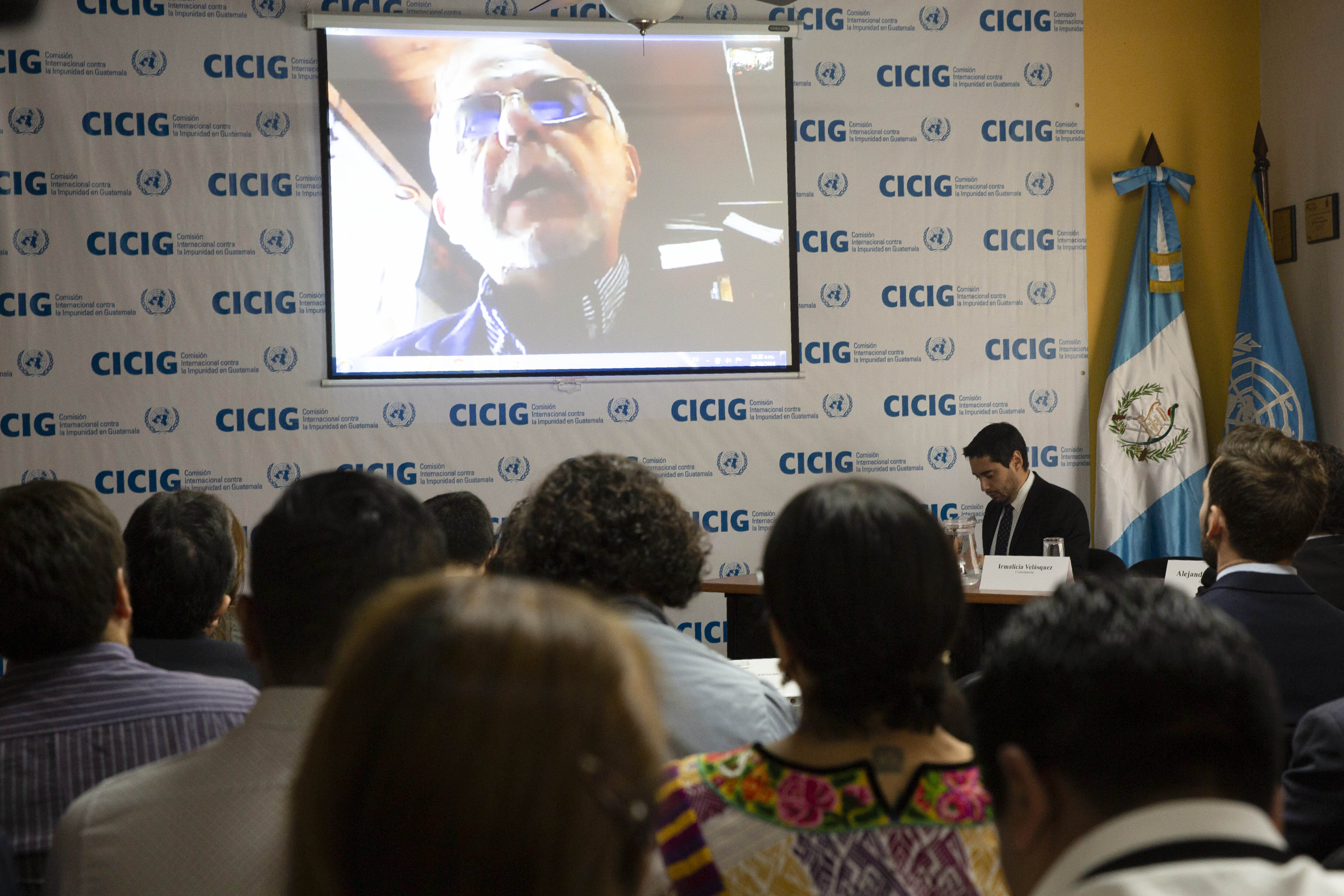 Ivan Velasquez, commissioner of the United Nations International Commission Against Impunity, CICIG, is seen on a screen during the presentation of a report titled "Guatemala, a Captured State", in Guatemala City, Wednesday, Aug. 28, 2019. The UN mission it's closing its operation after 12 years. It brought to trial three former presidents and hundreds of businessmen, officials, judges and individuals accused of corruption in the Central American country. (AP Photo/Moises Castillo)
