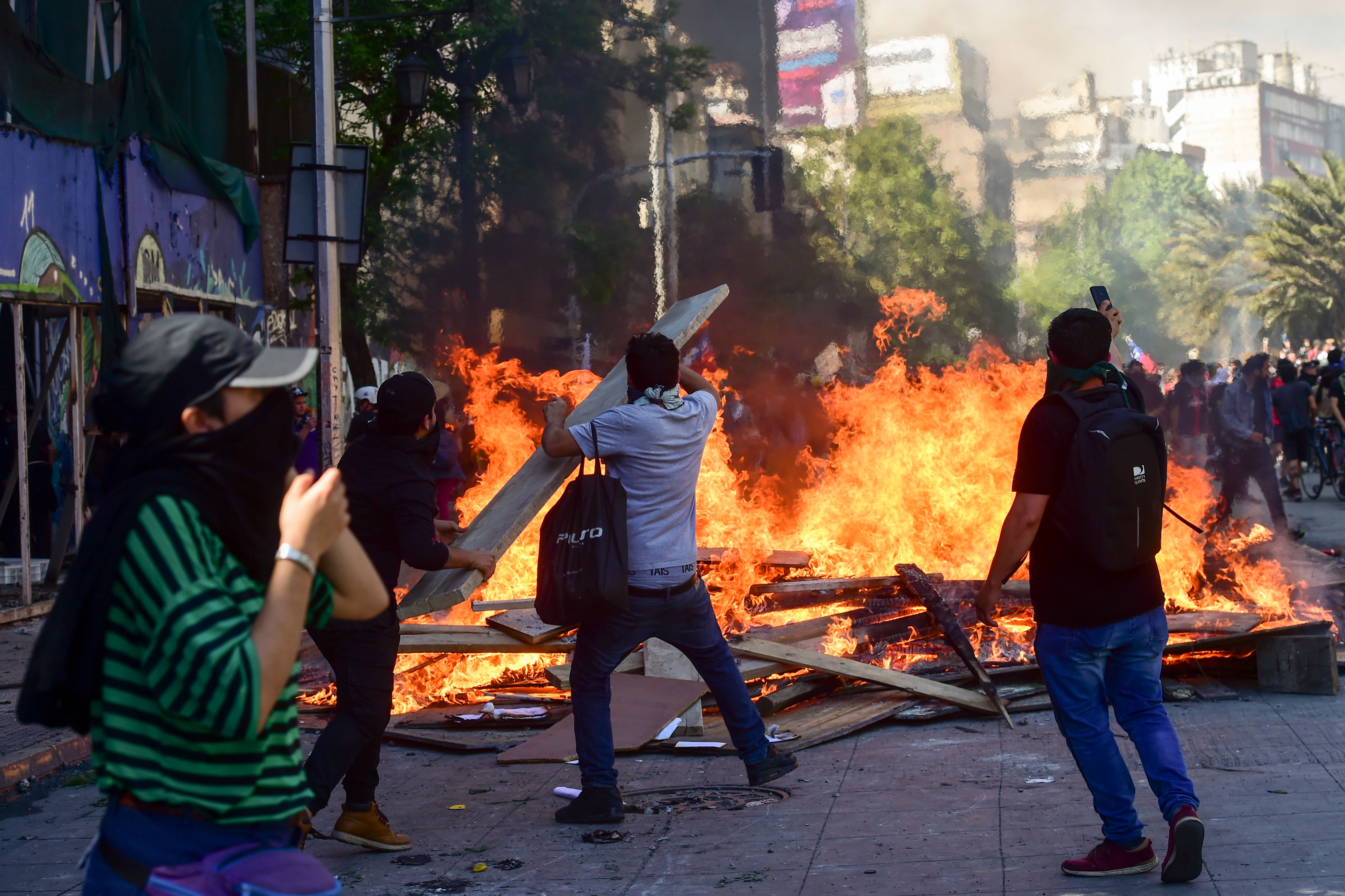 Demonstrators burn barricades during a protest in Santiago, Chile, on October 21, 2019. - Chile's death toll has risen to 11, authorities said on Monday, after three days of violent demonstrations and looting that saw President Sebastian Pinera claim the country was "at war." (Photo by Martin BERNETTI / AFP)
