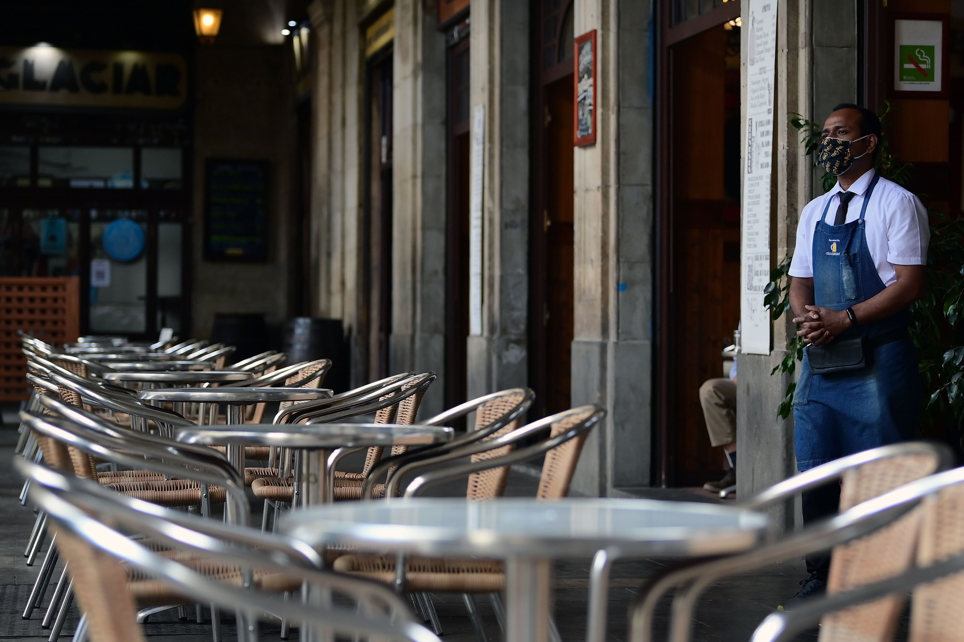 A waiter waits for customers at a restaurant in Barcelona on October 14, 2020. - Bars and restaurants are to be closed across Spain's northeastern Catalonia region for the next 15 days to slow rising coronavirus infections, the regional government said. (Photo by LLUIS GENE / AFP)