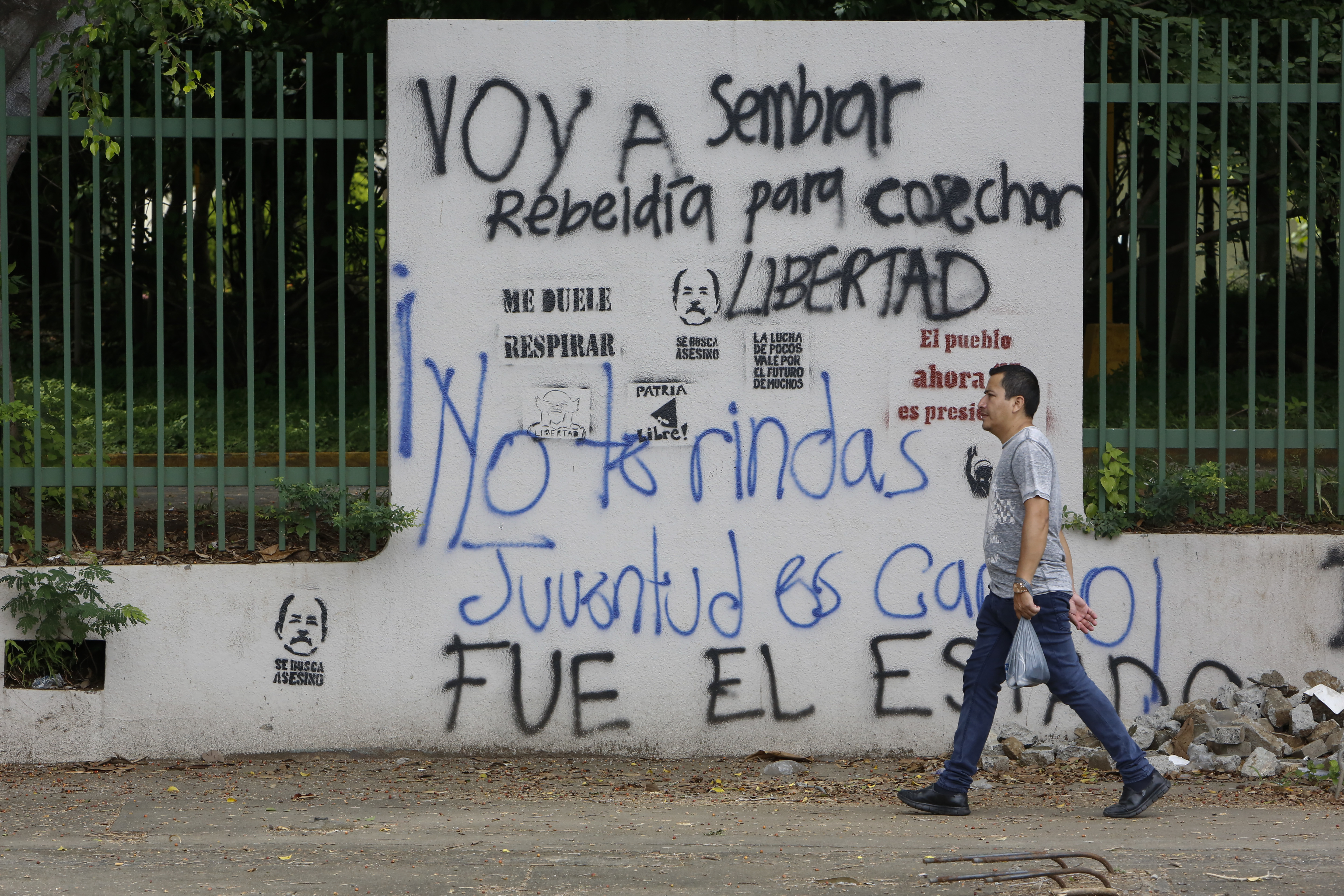 Un hombre camina cerca de un muro con grafitis en los alrededores de la Universidad Centroamericana, en Managua, Nicaragua. Foto: AP