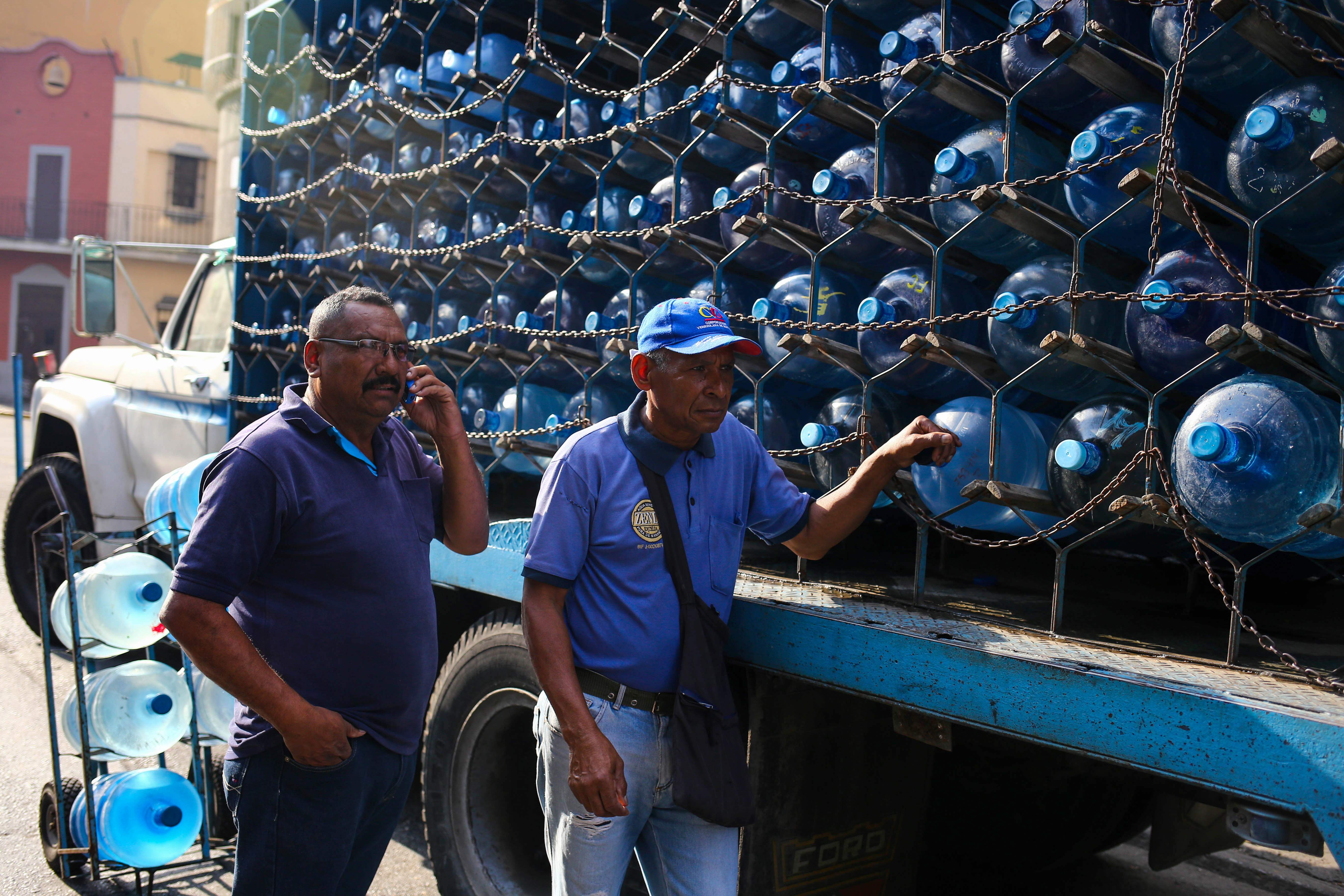 Workers deliver water cans in Caracas on March 27, 2019 during a power outage in Venezuela as a 24-hour closure of schools and workplaces has been extended another 24 hours to take a load off the grid. - Desperation and rage spreads among Venezuelans as the hours pass and the massive blackout that hits the country since Monday is not solved. A new blackout swept across Venezuela on Monday, including much of Caracas, sowing alarm two weeks after a nationwide outage that paralyzed the country. (Photo by Cristian HERNANDEZ / AFP)