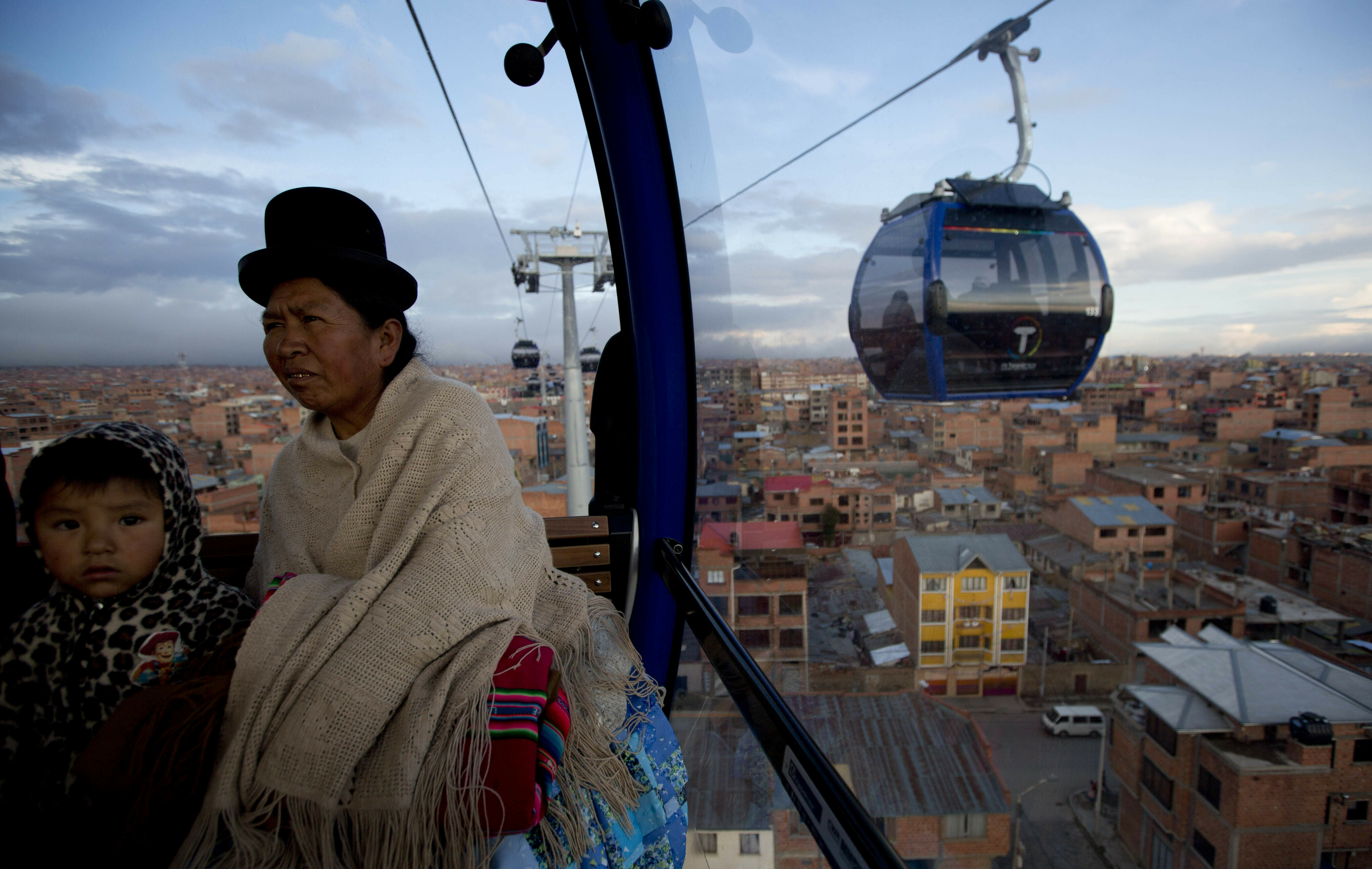 FILE - In this March 3, 2017 file photo, a woman and a child ride a cable car that interconnects the city El Alto, Bolivia. The cable car system is the world's highest, some 4 thousand meters above sea level. (AP Photo/Juan Karita, File)