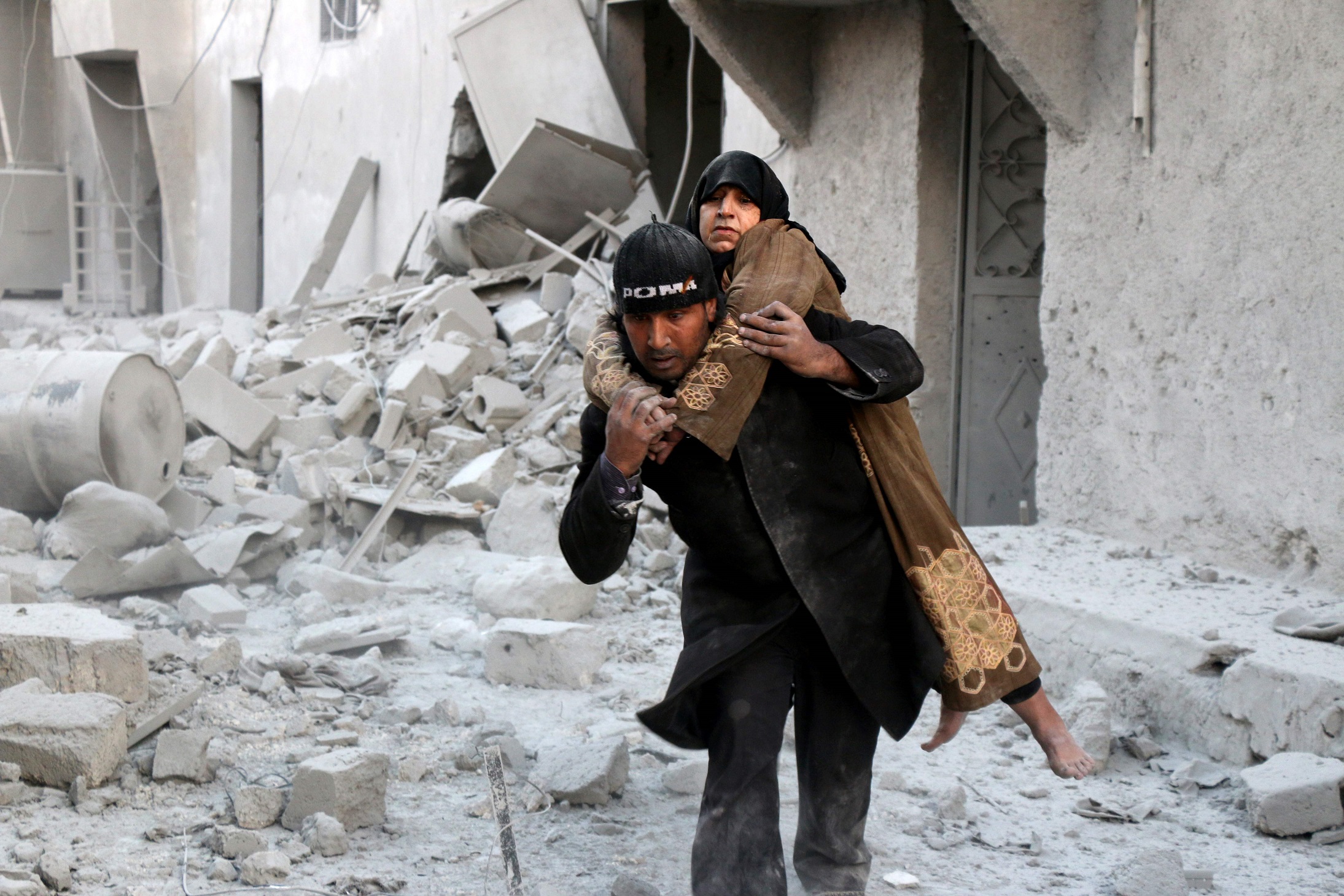Un hombre auxilia a esta mujer a quien rescató entre los escombros de un edificio bombardeado en el barrio rebelde de al-Hamra, en Alepo.