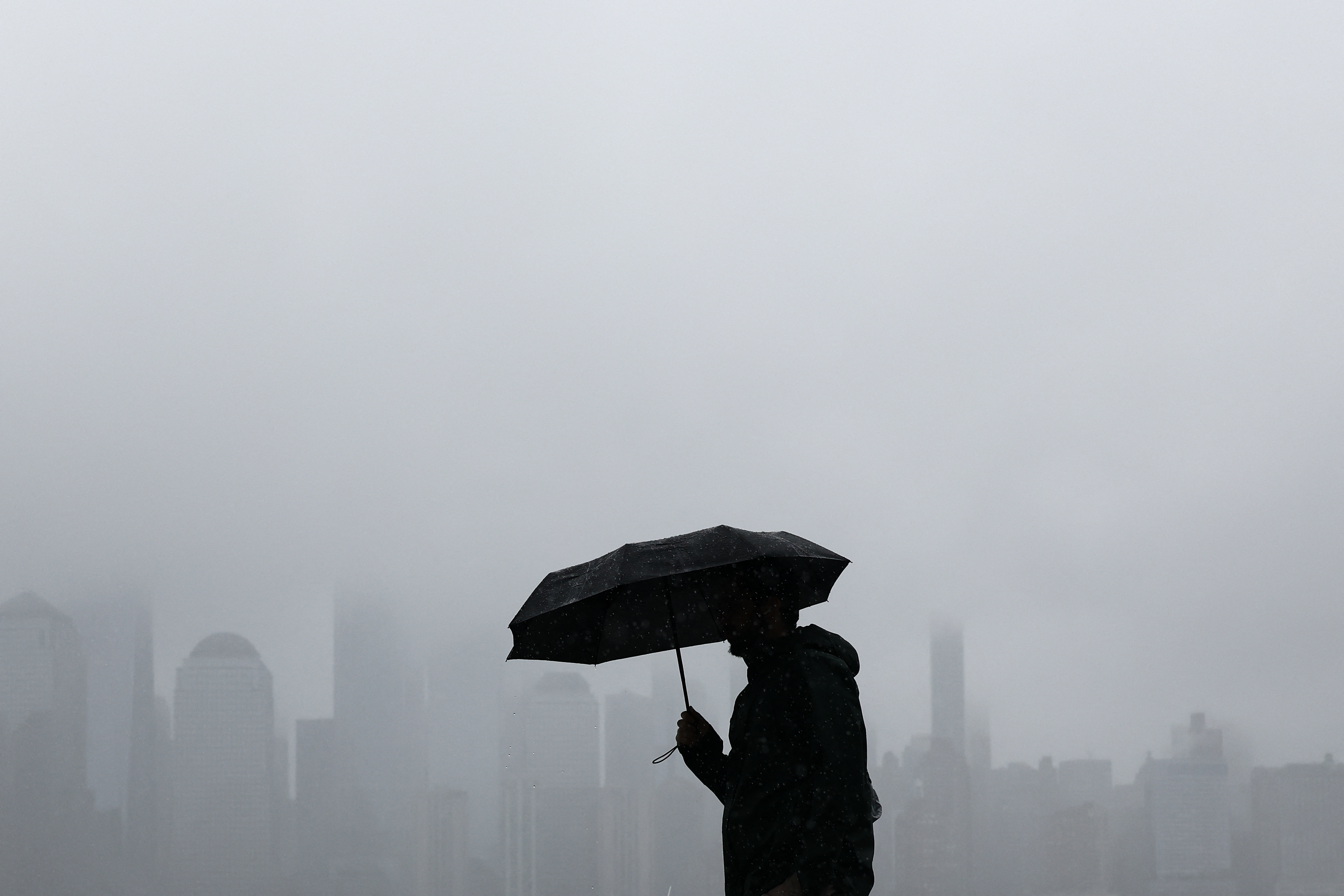 Una persona camina por la ribera de Jersey City, Nueva Jersey, mientras el perfil de Lower Manhattan se vislumbra entre la niebla, el 27 de setiembre de 2026.
