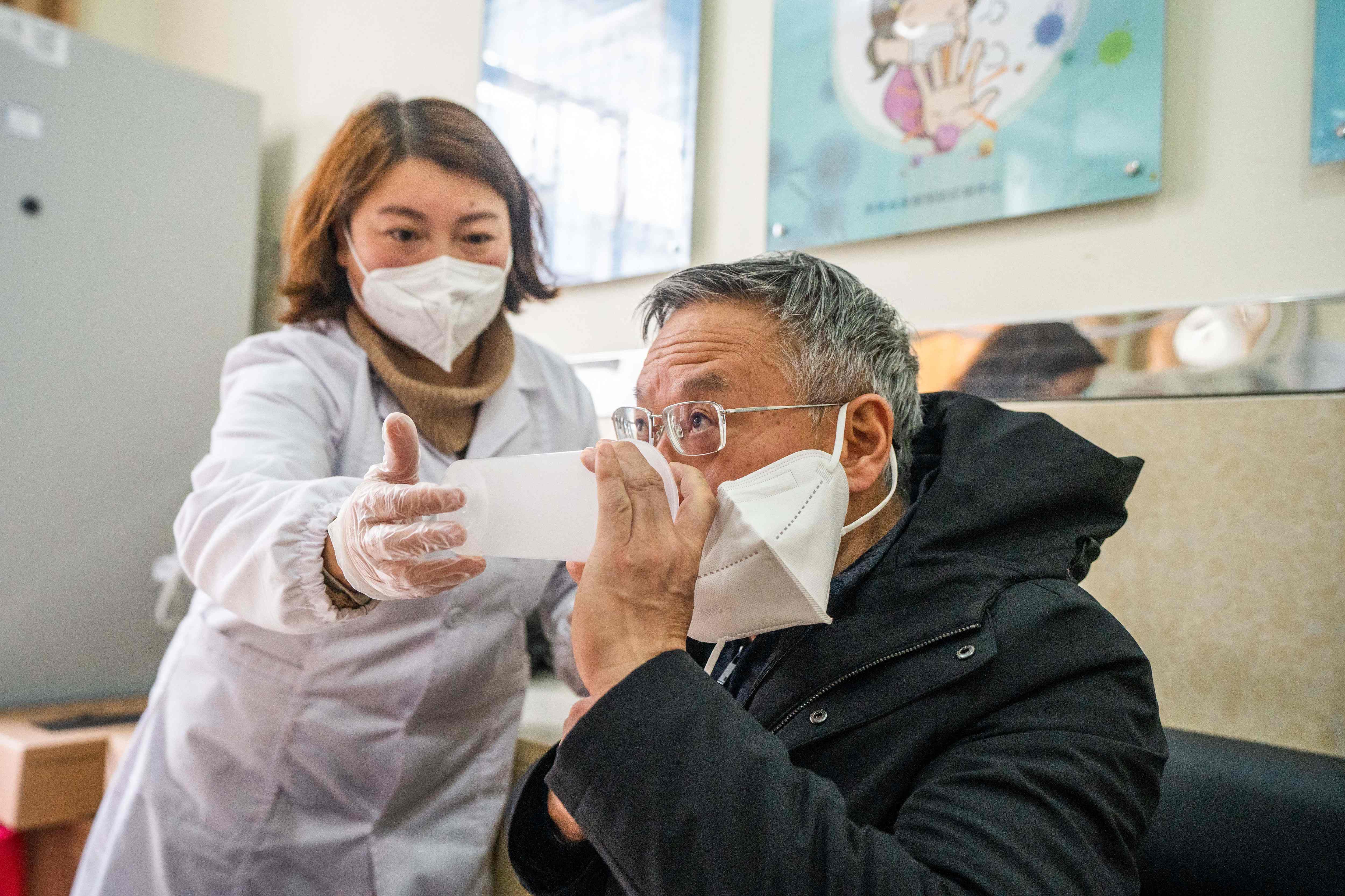 This photo taken on December 29, 2022 shows a health worker administering a dose of CanSino Biologics inhalable Covid-19 coronavirus vaccine in Bijie, in China's southwestern Guizhou province. (Photo by AFP) / China OUT
