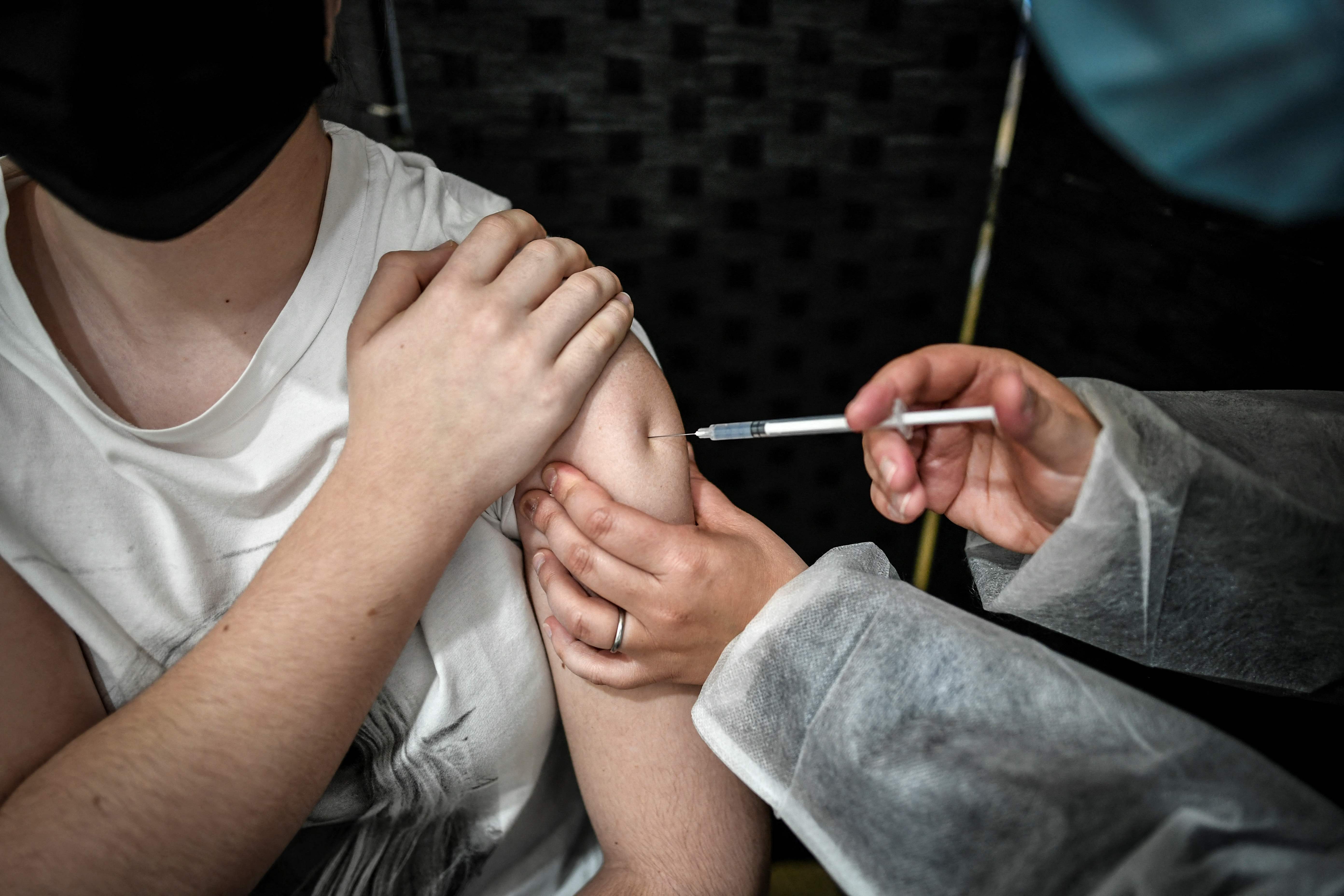 A patient receives a dose of the Pfizer-BioNTech vaccine against the Covid-19 at the temporary Covid-19 vaccination centre at the 'Orangerie' of Versailles Palace in Versailles on May 29, 2021. (Photo by STEPHANE DE SAKUTIN / AFP)