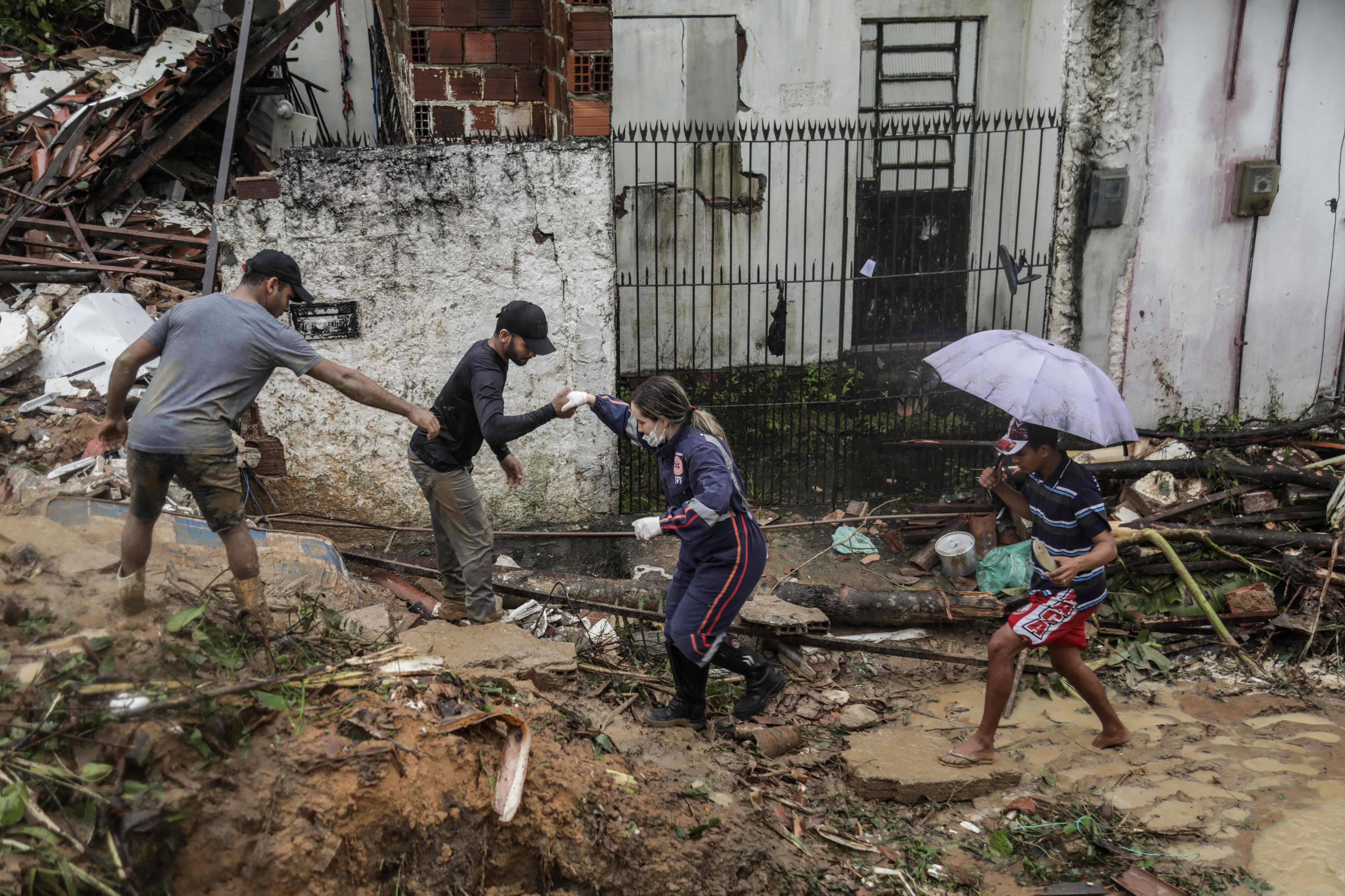 TOPSHOT - This handout picture release by the Recife City Hall shows residents and rescue workers walking amid the debris of a landslide that destroyed several houses in the community Jardim Monte Verde, Ibura neighbourhood, in Recife, Pernambuco State, Brazil, on May 28, 2022. - Torrential rains that have plagued Brazil's northeastern Pernambuco state since Tuesday have left at least 34 dead, 29 of which occurred over the last 24 hours, according to the latest official update. (Photo by Diego NIGRO / RECIFE CITY HALL / AFP) / RESTRICTED TO EDITORIAL USE - MANDATORY CREDIT "AFP PHOTO / RACIFE CITY HALL / DIEGO NIGRO" - NO MARKETING - NO ADVERTISING CAMPAIGNS - DISTRIBUTED AS A SERVICE TO CLIENTS