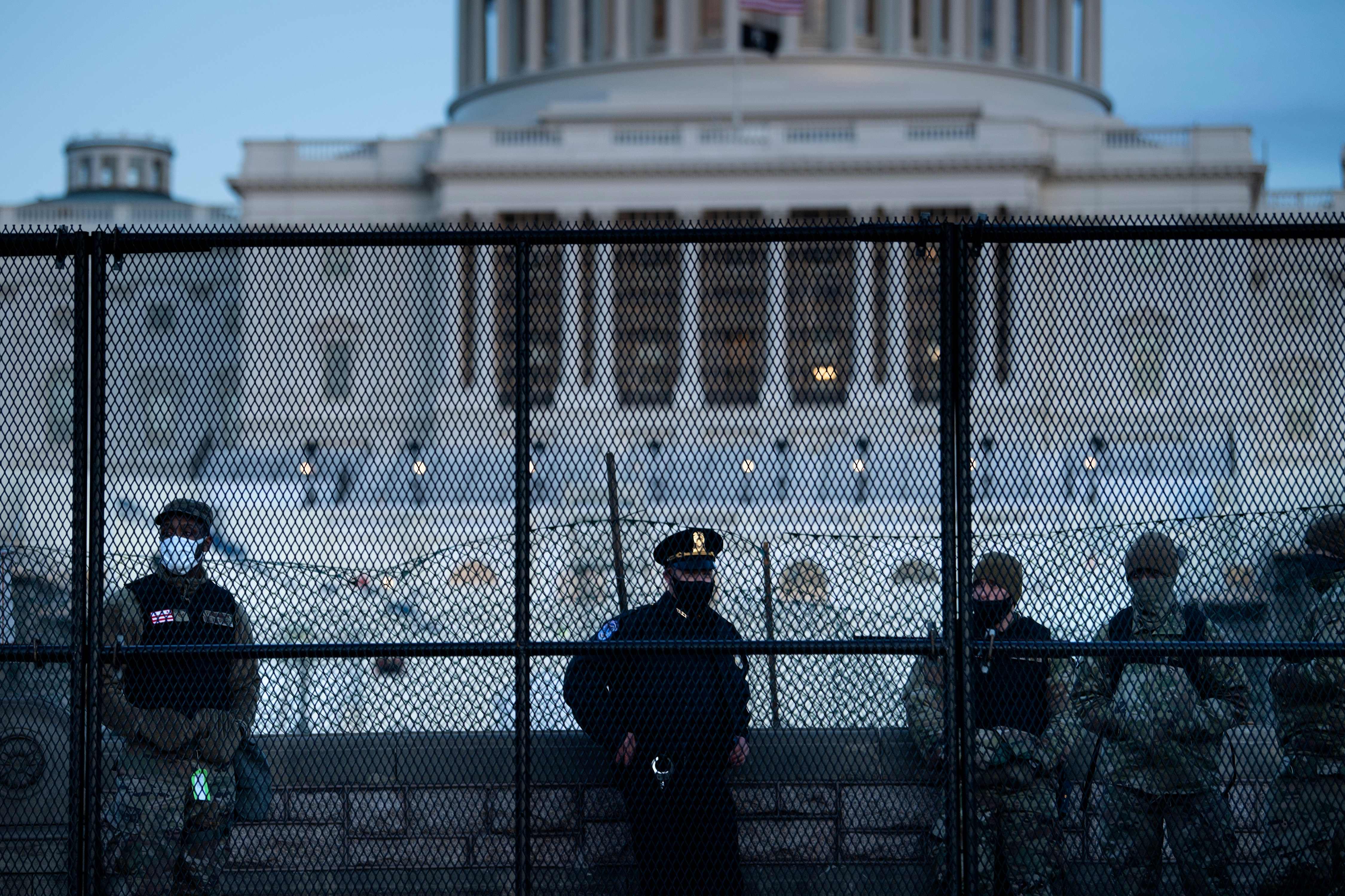 A Capitol Police officer stands with members of the National Guard behind a crowd control fence surrounding Capitol Hill a day after a pro-Trump mob broke into the US Capitol on January 7, 2021, in Washington, DC. (Photo by Brendan Smialowski / AFP)