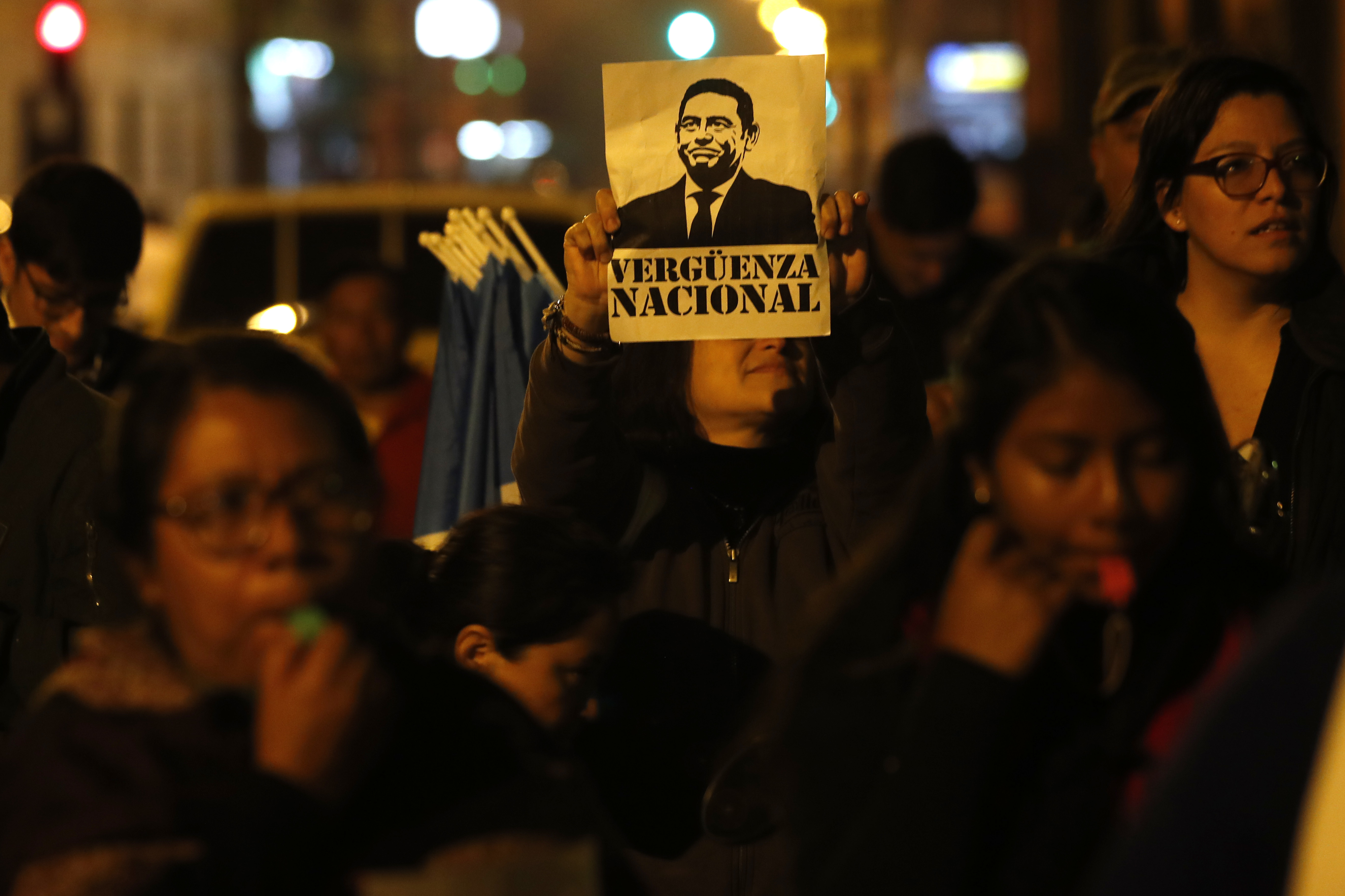 A woman holds up a sign with portrait of Guatemalan President Jimmy Morales that reads in Spanish "national shame," during a rally in support of the United Nations International Commission Against Impunity, CICIG, in Guatemala City, Tuesday, Jan. 8, 2019. A decade-long, U.N.-assisted anti-corruption effort that brought down a president faced extinction after the Guatemalan government ended the agreement, drawing condemnation Tuesday from transparency and rights groups. (AP Photo/Moises Castillo)