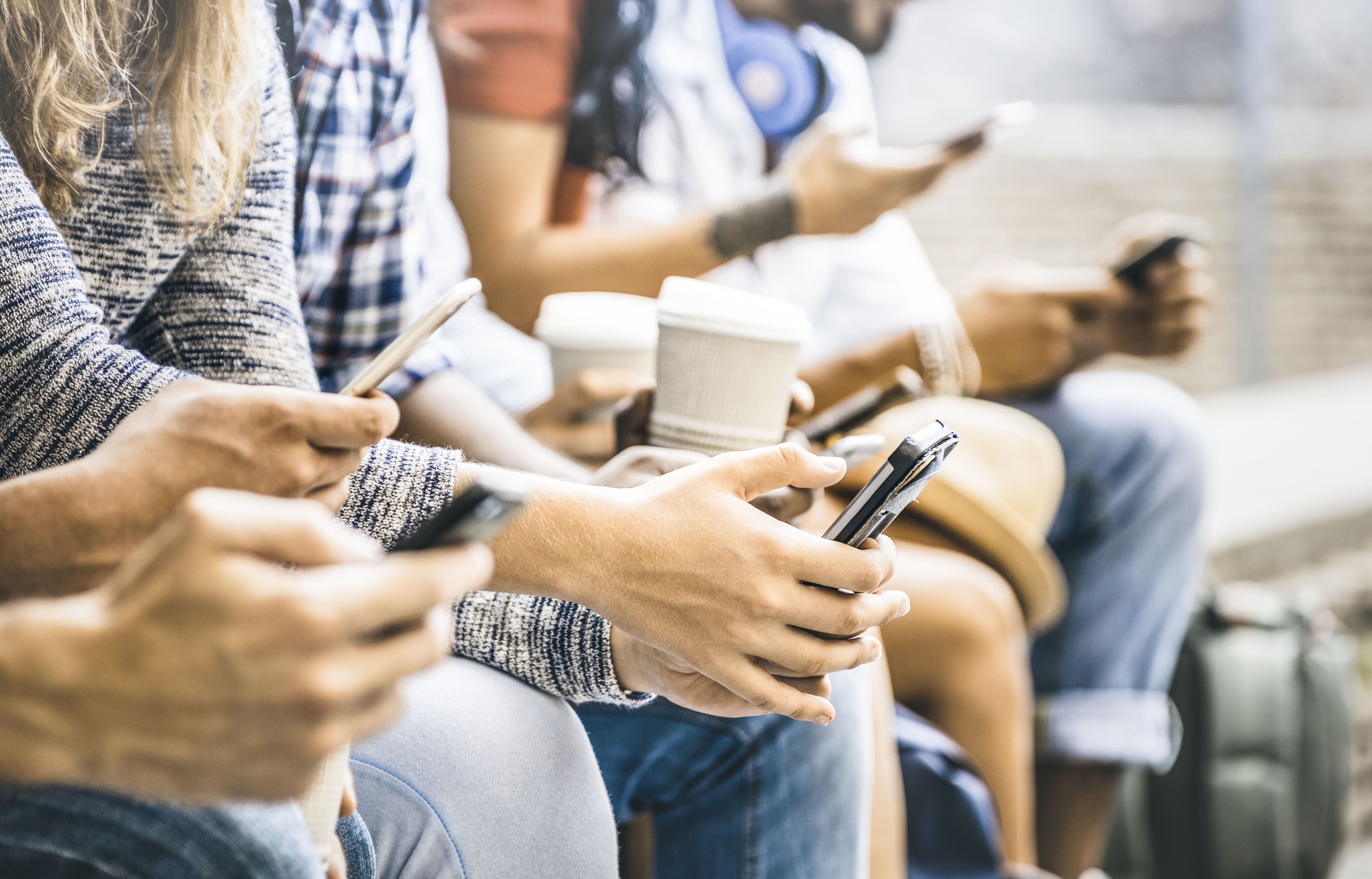 Personas sosteniendo teléfonos móviles mientras consultan información en redes sociales, destacando el rol de plataformas como TikTok, YouTube y WhatsApp en la difusión de noticias.