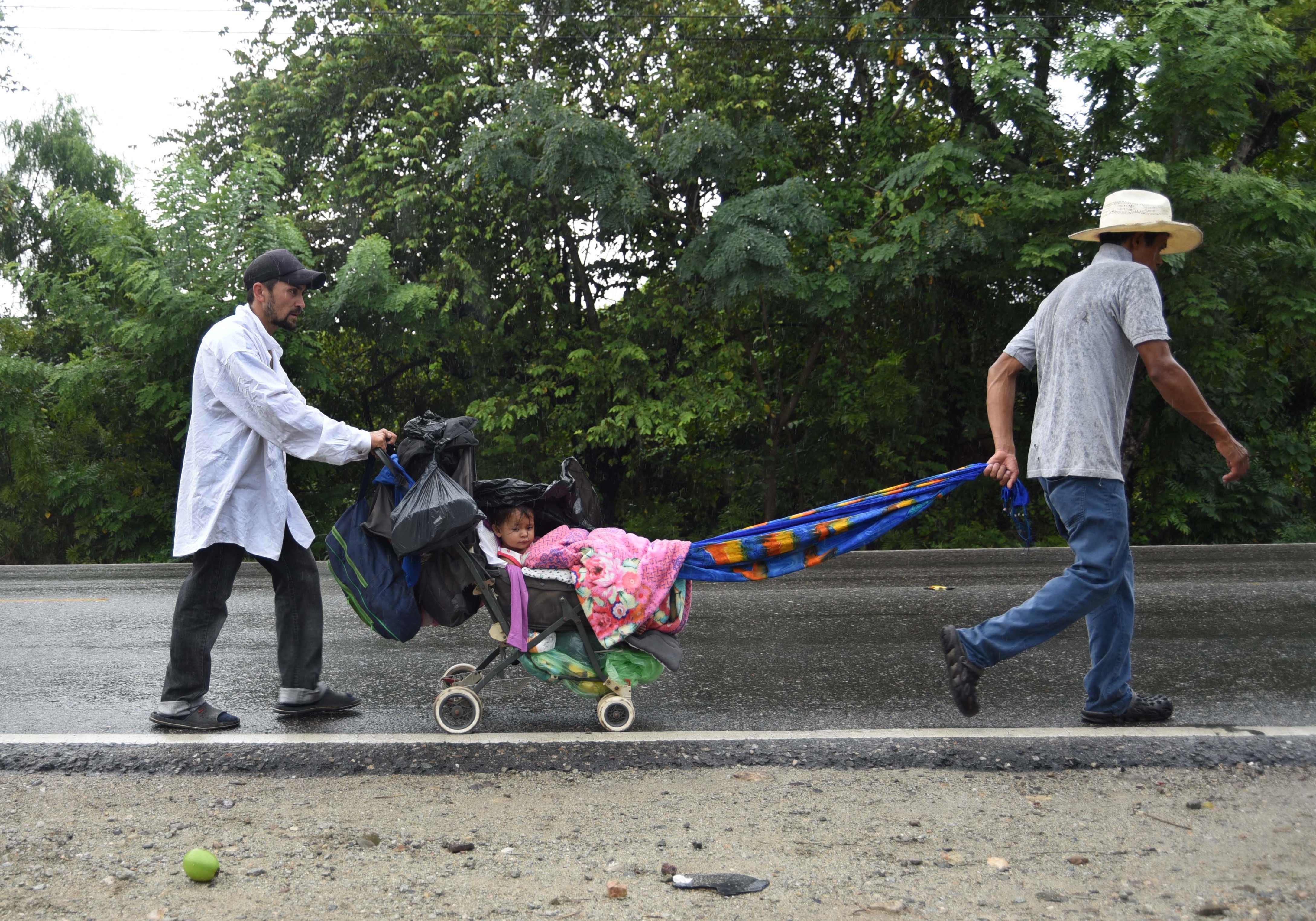 Los migrantes hondureños empujan un coche con un bebé mientras participan en una caravana hacia Estados Unidos, en Zacapa, 145 km al este de la Ciudad de Guatemala. Foto: AFP