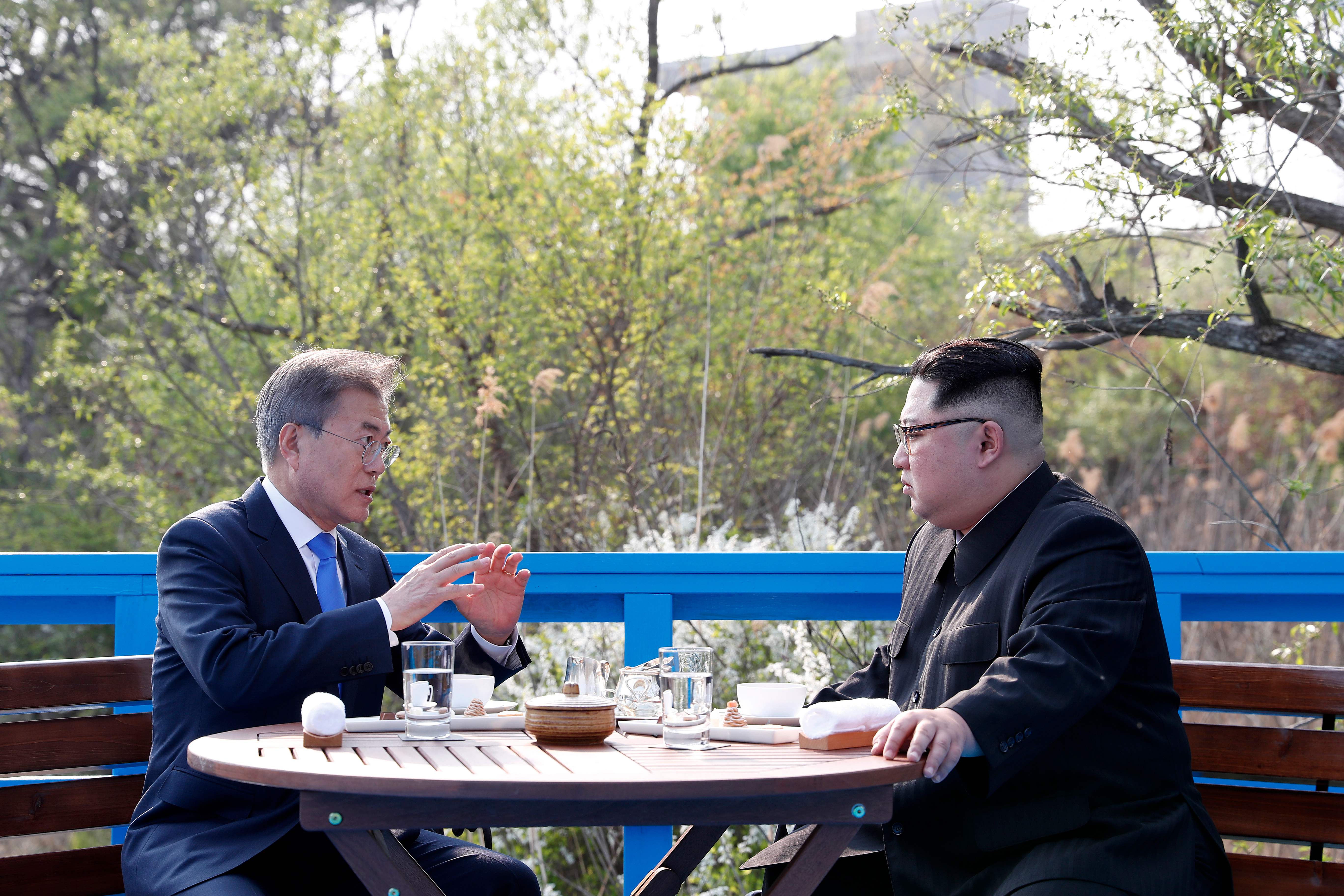 North Korea's leader Kim Jong Un (R) talks with South Korea's President Moon Jae-in (L) at a bench on a bridge next to the military demarcation line at the truce village of Panmunjom on April 27, 2018.
The leaders of the two Koreas held a landmark summit on April 27 after a highly symbolic handshake over the Military Demarcation Line that divides their countries, with the North's Kim Jong Un declaring they were at the "threshold of a new history". / AFP PHOTO / Korea Summit Press Pool / Korea Summit Press Pool