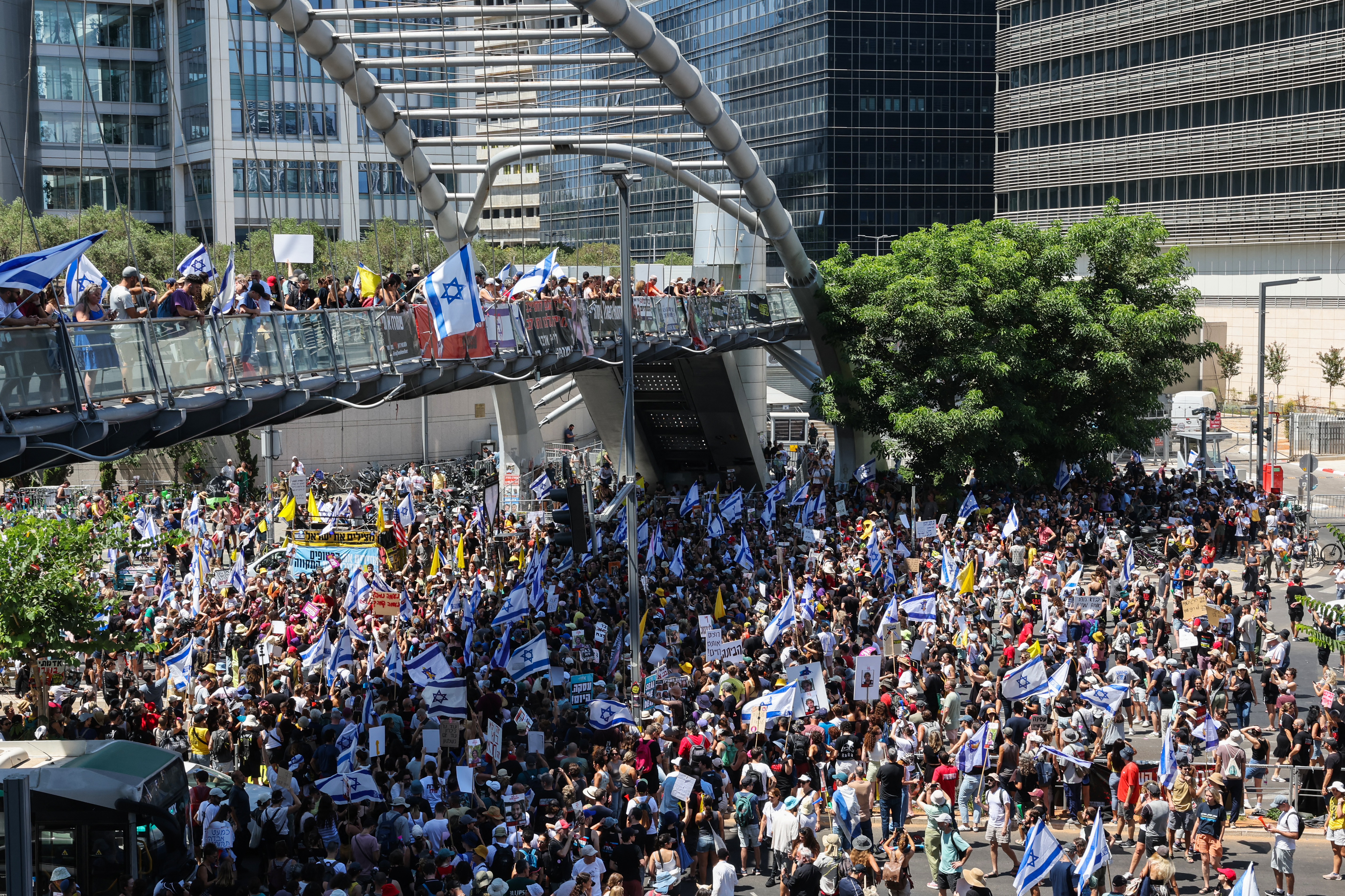 Familiares y simpatizantes de los rehenes israelíes retenidos por militantes palestinos en la Franja de Gaza desde octubre levantan banderas y carteles durante una manifestación en Tel Aviv.
