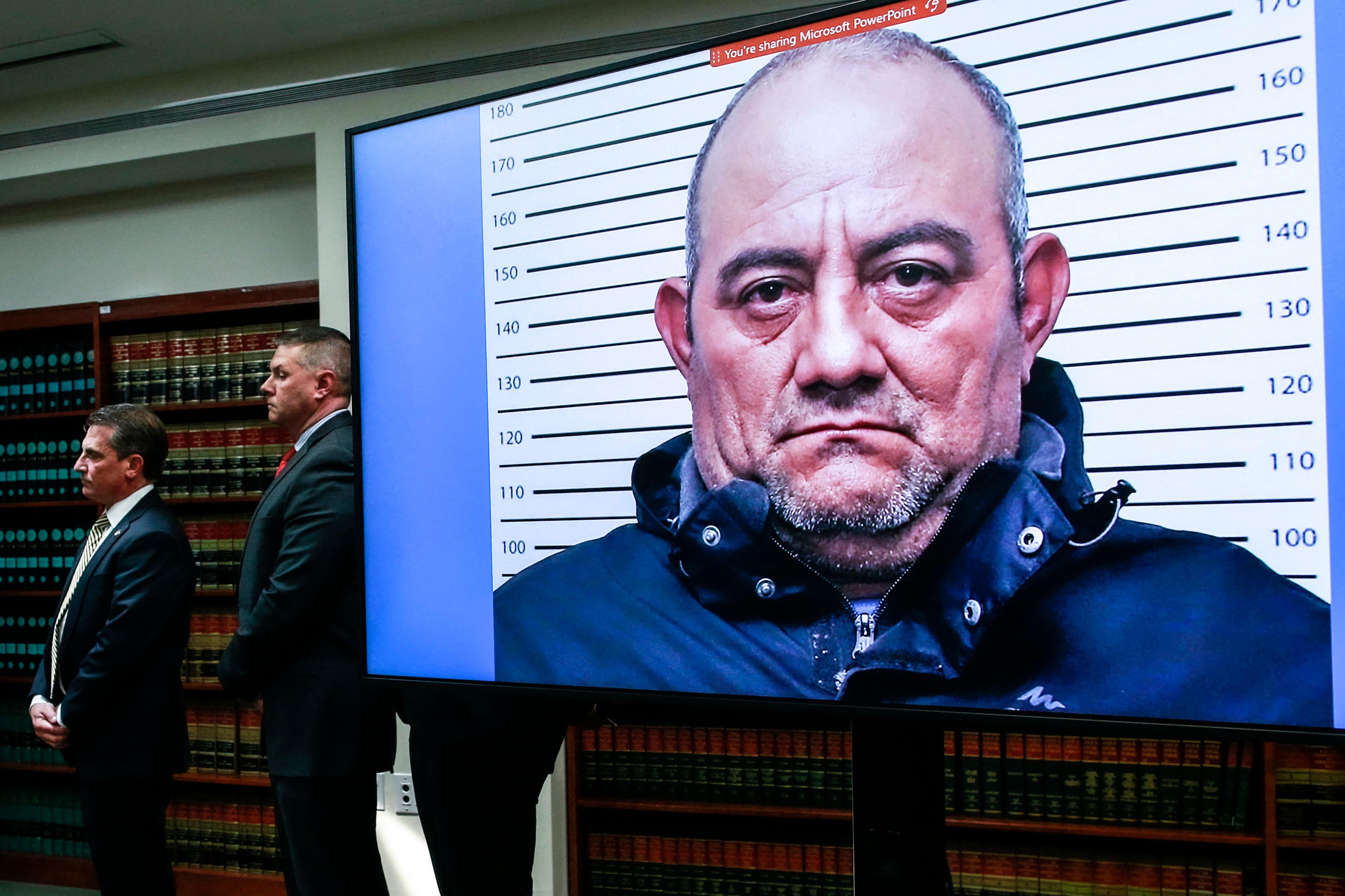 TOPSHOT - A picture of Colombian drug lord Dairo Antonio Usuga, aka Otoniel, is displayed on a screedn as Eastern District of New York Attorney Breon Peace (out of frame) speaks during a press conference about his extradition in New York City on May 5, 2022. - One of Colombia's most notorious drug lords was extradited Wednesday to the United States to face drug trafficking charges, announced President Ivan Duque. "I want to reveal that Dairo Antonio Usuga, alias 'Otoniel' has been extradited," Duque said on Twitter, calling him "the most dangerous drug trafficker in the world." (Photo by Kena Betancur / AFP)