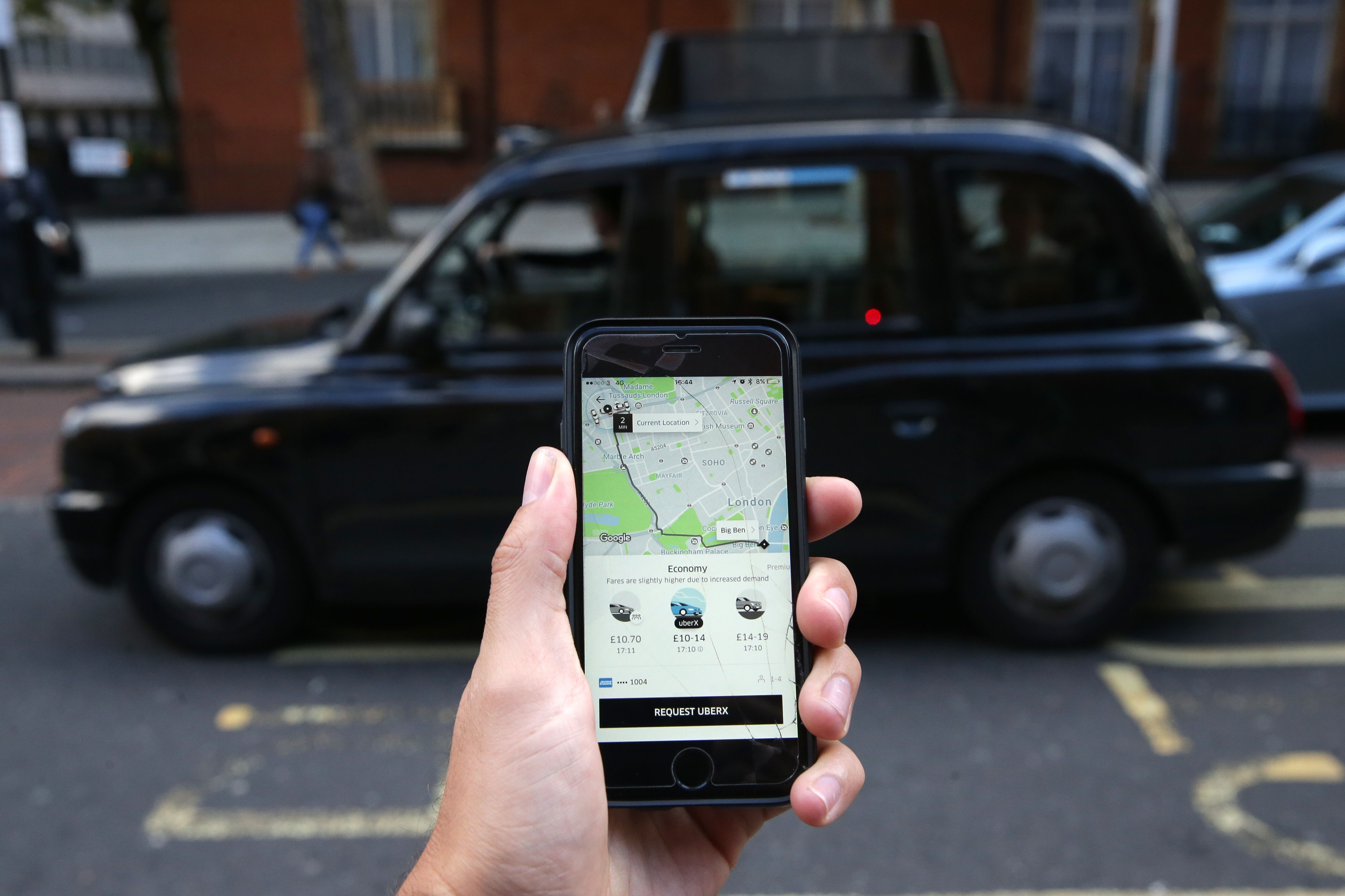 (FILES) In this file photo taken on September 22, 2017 A woman poses holding a smartphone showing the App for ride-sharing cab service Uber in London. - London's transport authority on November 25, 2019 refused to renew an operating licence for the ride-hailing giant Uber because of safety and security concerns. (Photo by Daniel LEAL-OLIVAS / AFP)